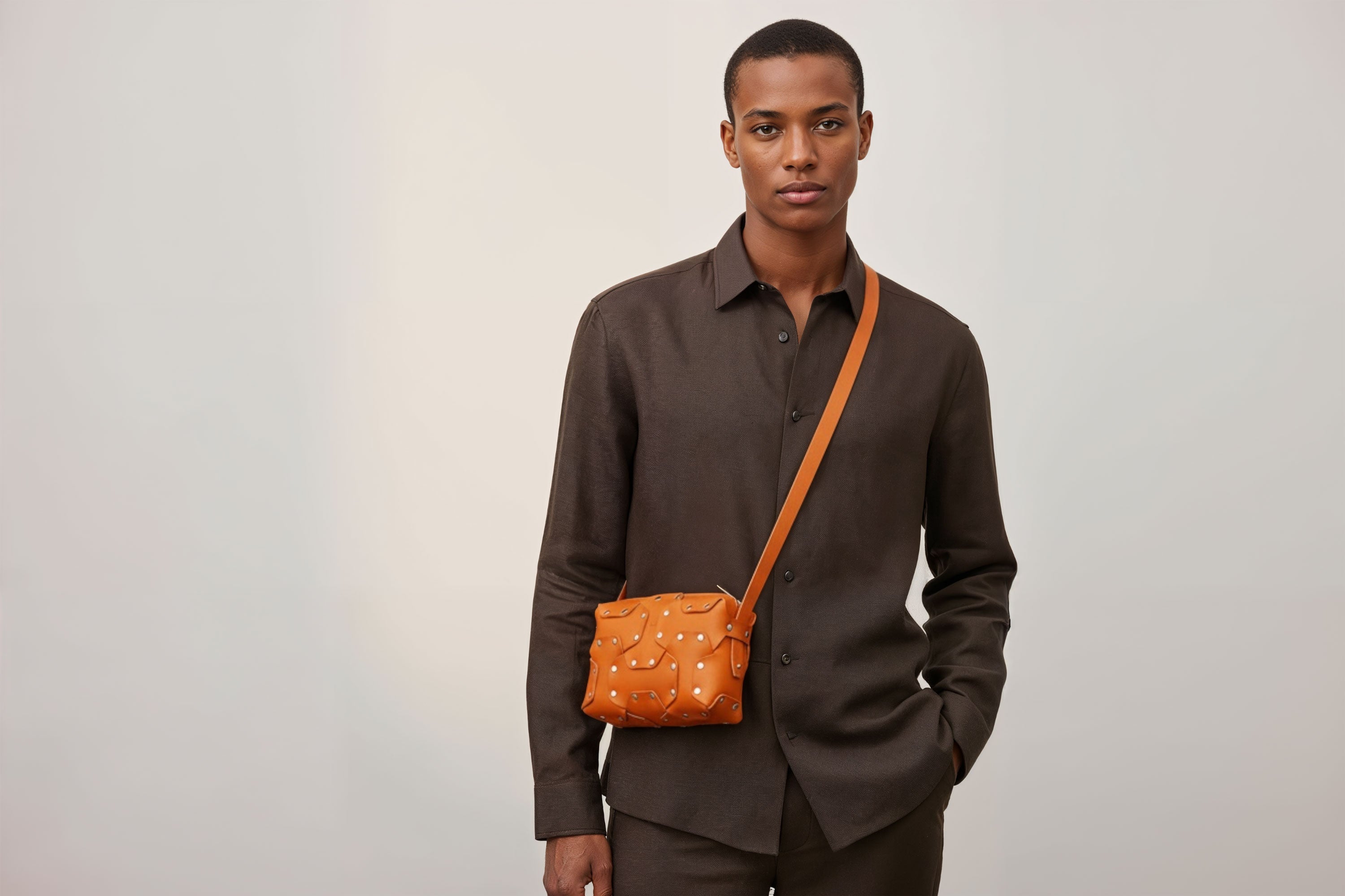 Double Rivet Bag Orange Color On A Man Model Leather Full Grain Vegetable Tanned Leather Modern Minimalist Design Premium Quality Full Brass Clutch Crossbody Shoulder Bag Atelier Madre Manuel Dreesmann Barcelona Spain