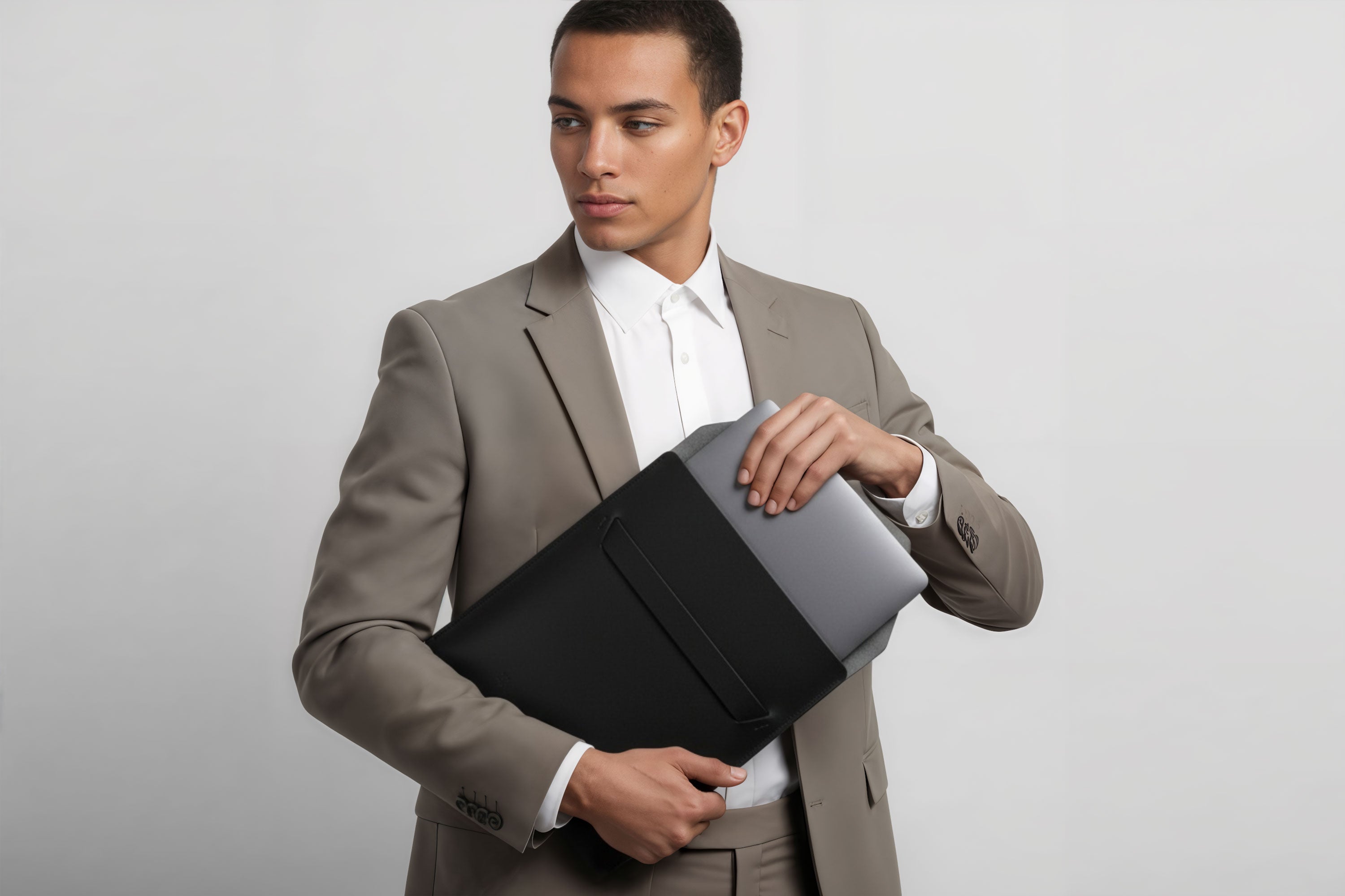 Man holding a leather sleeve for a MacBook in black color in front of bright background minimalistic design atelier Madre Manuel Dreesmann Barcelona Spain