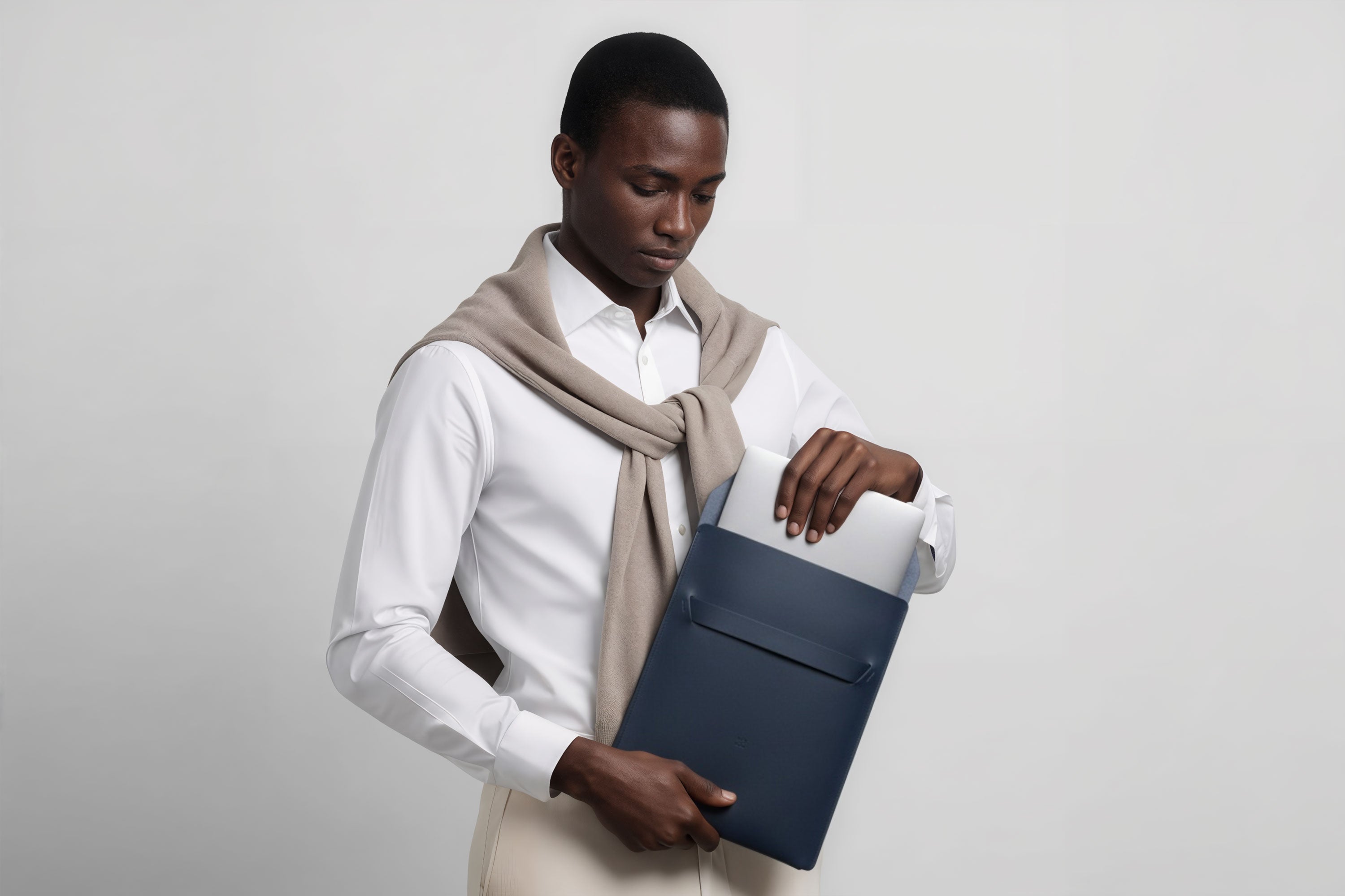 Man holding a leather sleeve for a MacBook in marine blue color in front of bright background minimalistic design atelier Madre Manuel Dreesmann Barcelona Spain