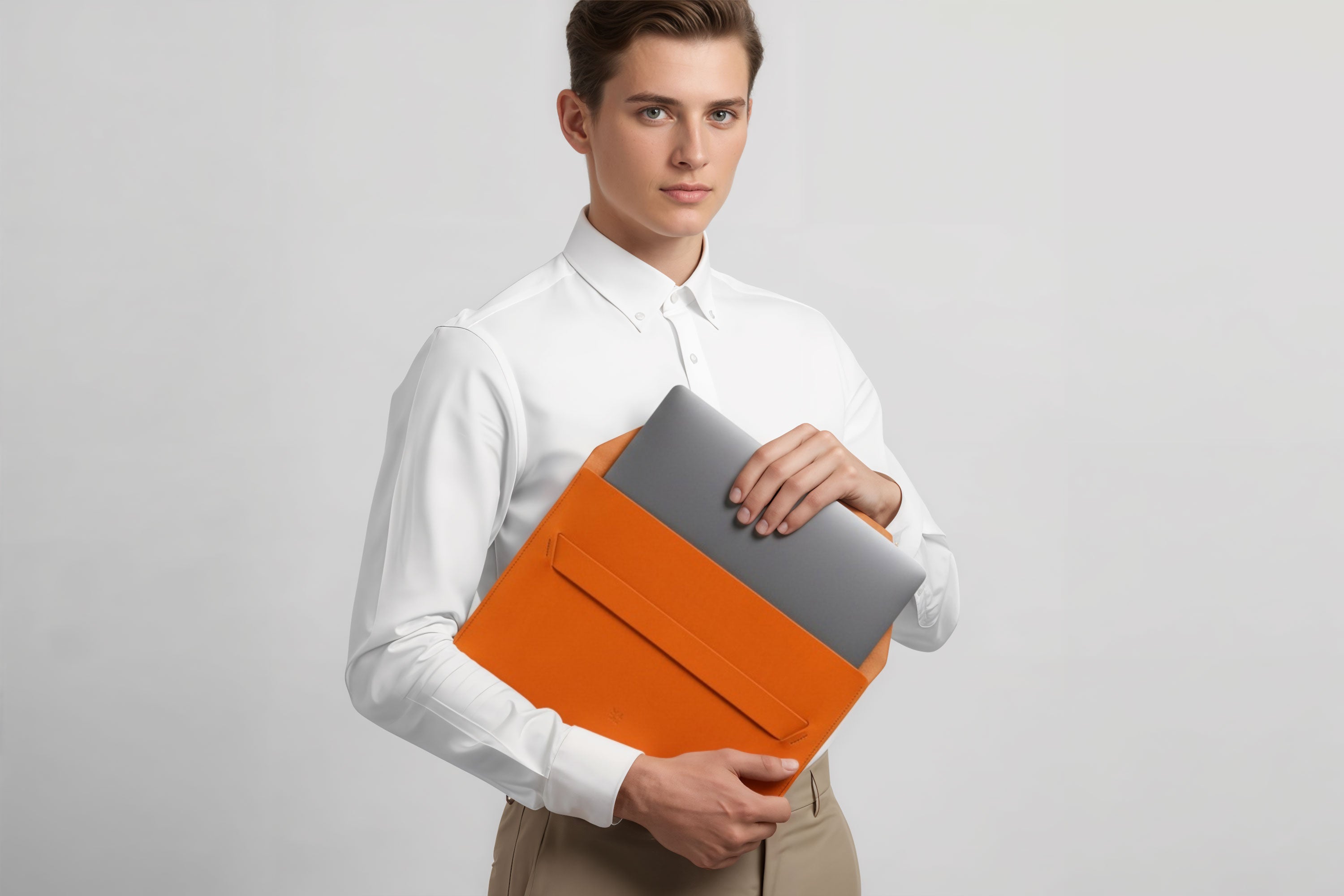 Man holding a leather sleeve for a MacBook in orange color in front of bright background minimalistic design atelier Madre Manuel Dreesmann Barcelona Spain