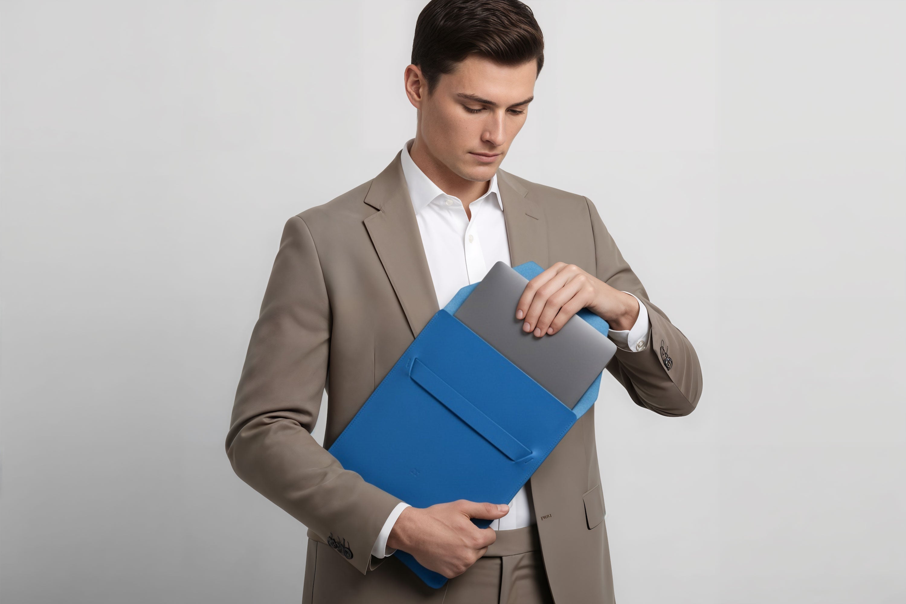 Man holding a leather sleeve for a MacBook in royla blue color in front of bright background minimalistic design atelier Madre Manuel Dreesmann Barcelona Spain