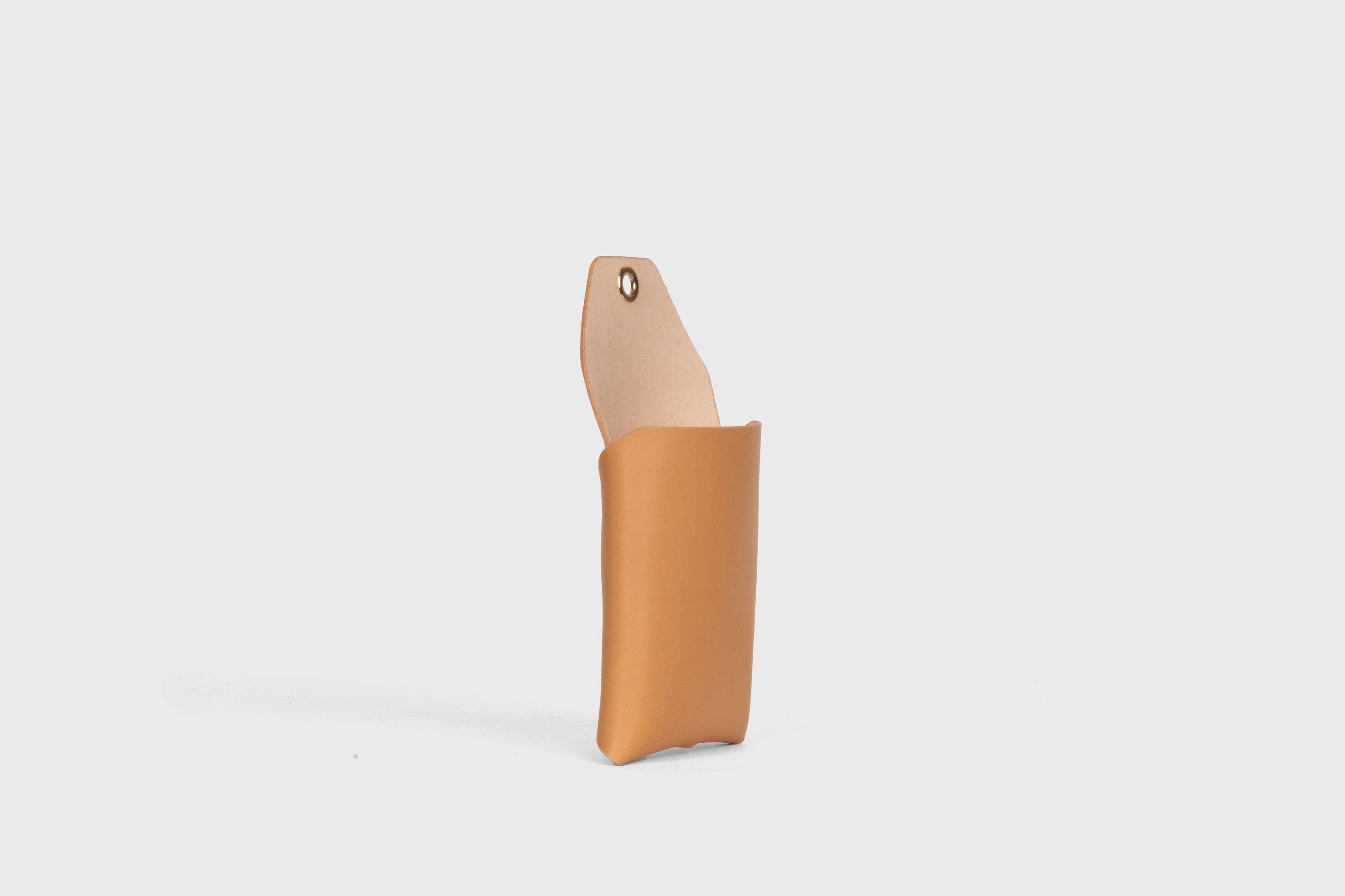 Suporte de parede para telemóvel em pele curtida vegetal de cor castanha Design minimalista com um ilhó com um orifício para o cabo de carregamento Atelier Madre Manuel Dreesmann Barcelona Espanha