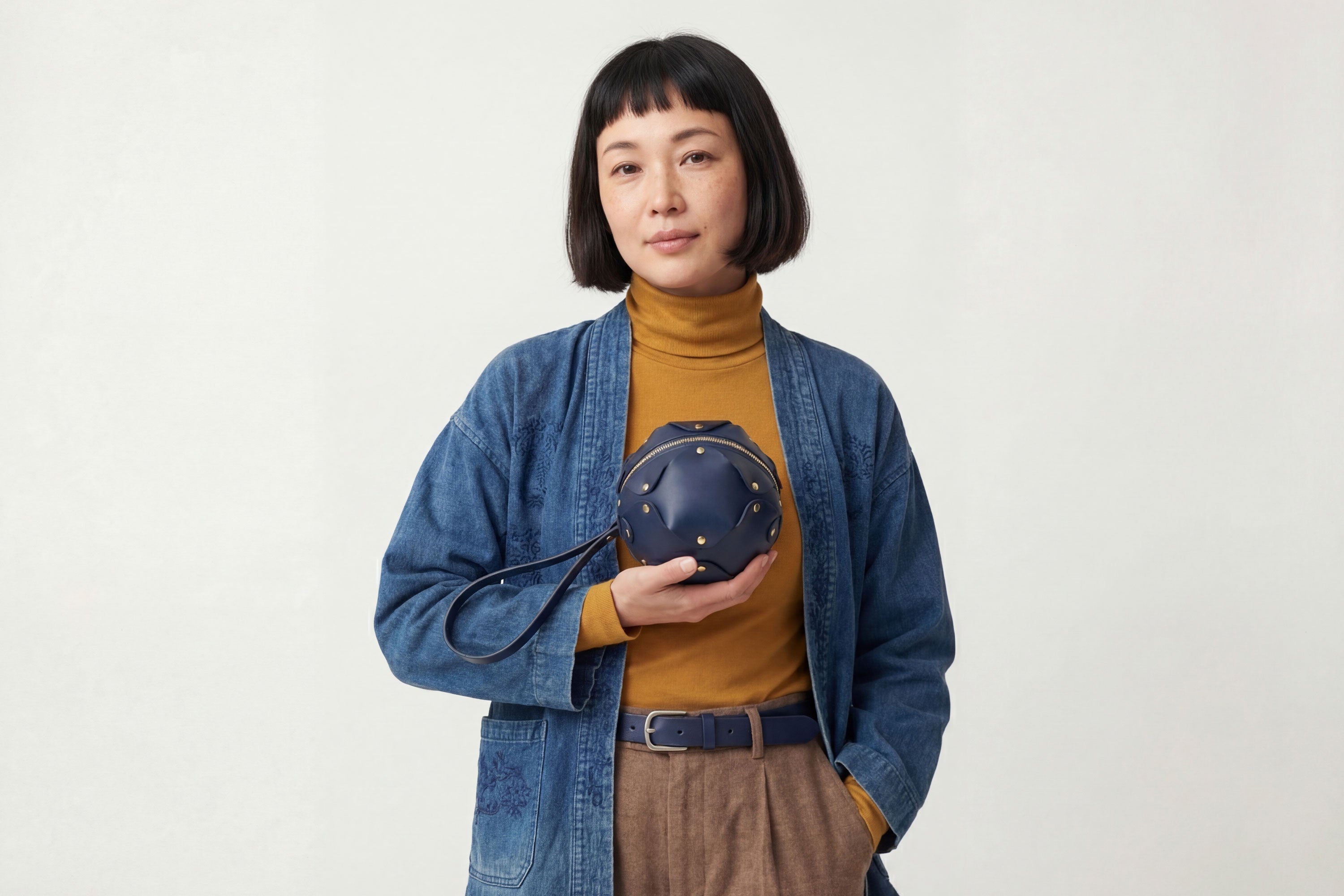 Puff Leather Ball Bag Marine Blue Color On A Woman Model Luxury Vegetable Tanned Full Grain Spain Brass Rivets Premium Design Minimalist Modern Round Sphere Circle Round Zipper Pouch Handbag Clutch Bag Atelier Madre Manuel Dreesmann Barcelona