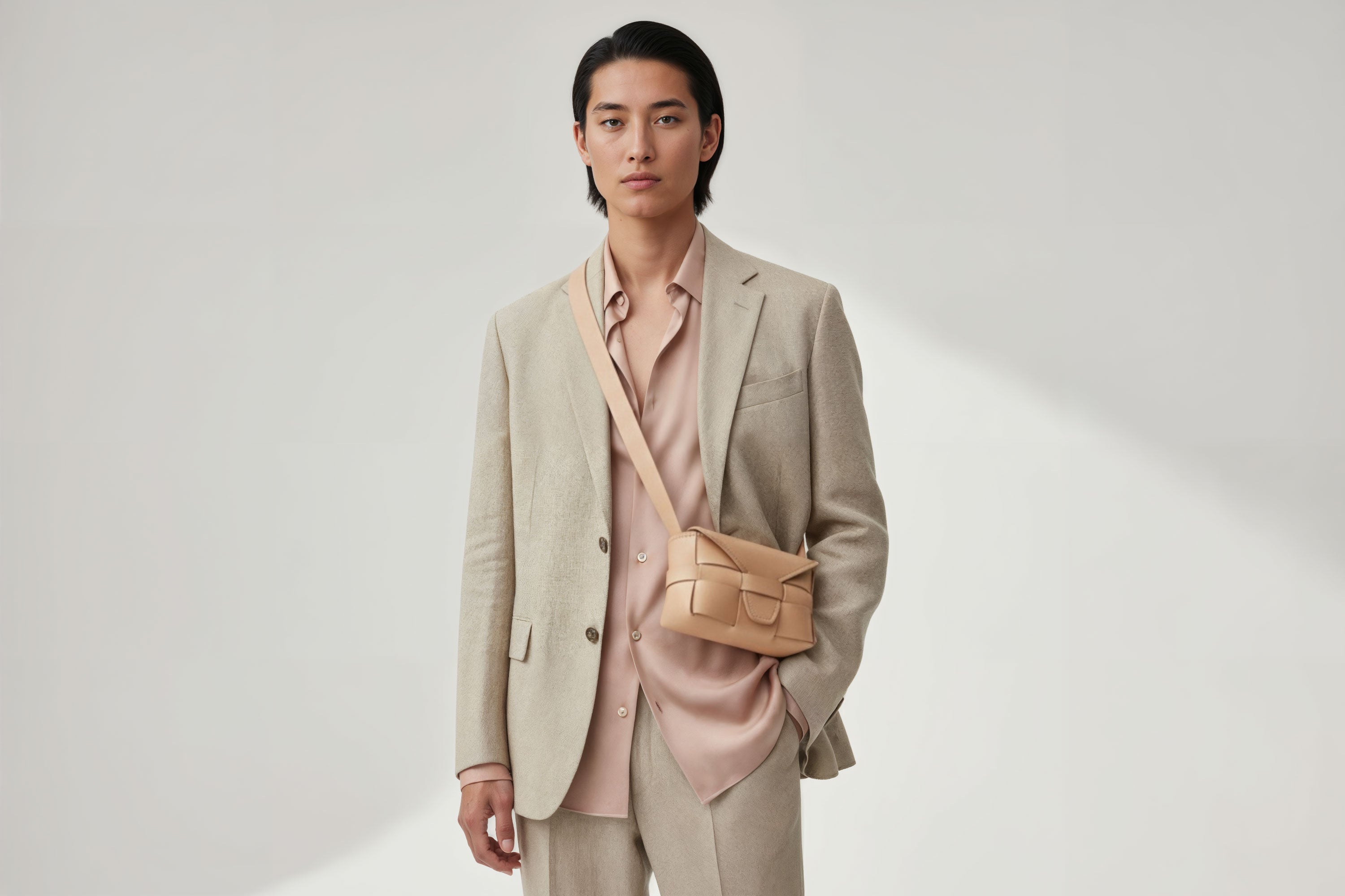 Man wearing the natural color small Saka leather bag against a plain background. Minimalist design from Atelier Madre - Manuel Dreesmann in Barcelona