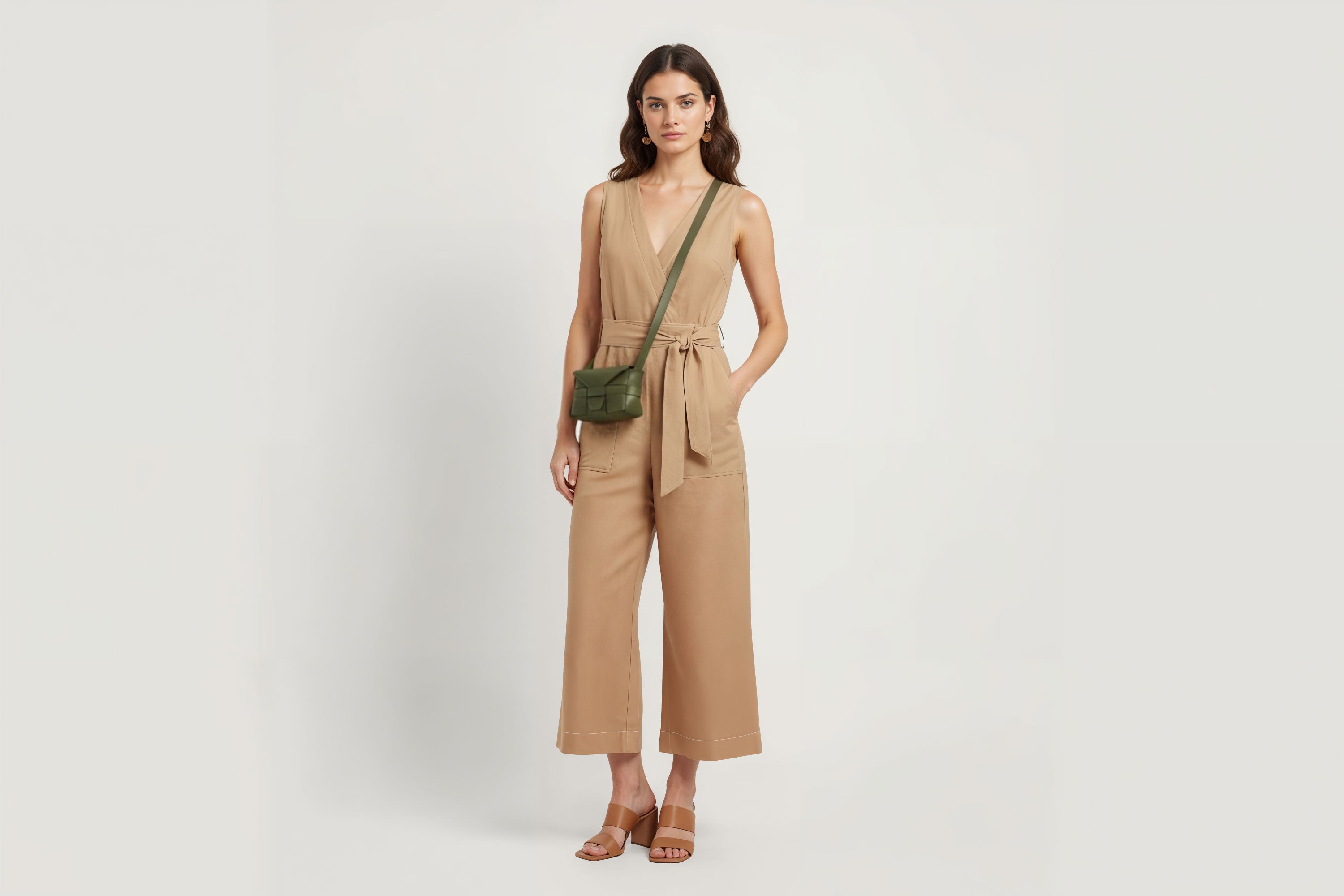 Woman wearing the olive green small Saka leather bag against a plain background. Minimalist design from Atelier Madre - Manuel Dreesmann in Barcelona