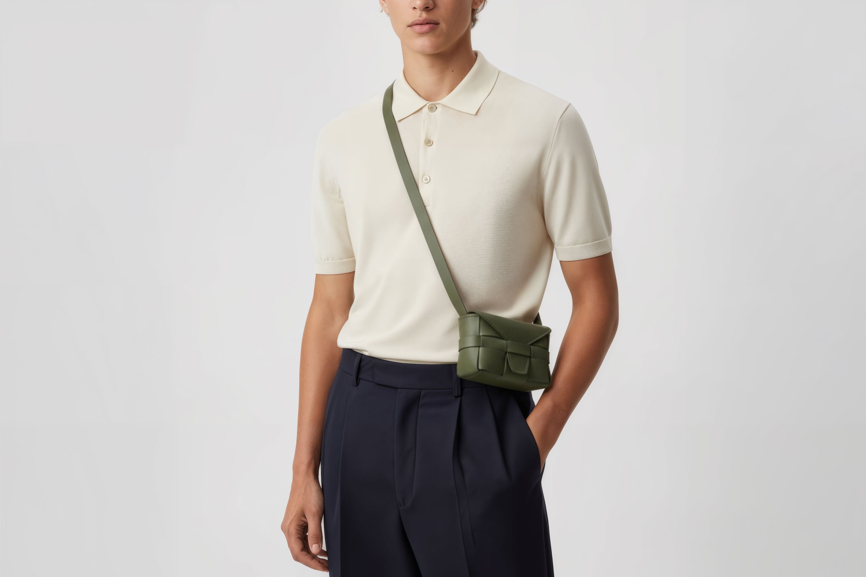 man wearing the olive green small Saka leather bag against a plain background. Minimalist design from Atelier Madre - Manuel Dreesmann in Barcelona