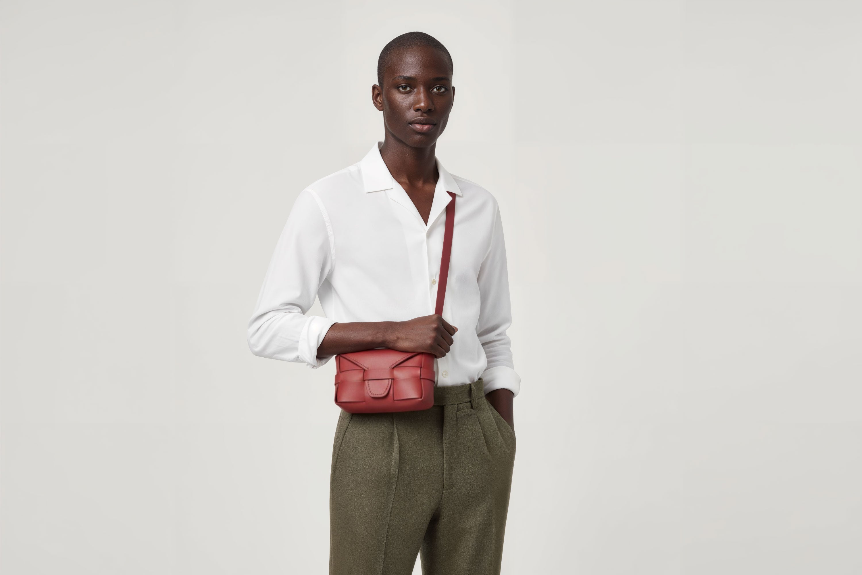 Man wearing the red small Saka leather bag against a plain background. Minimalist design from Atelier Madre - Manuel Dreesmann in Barcelona