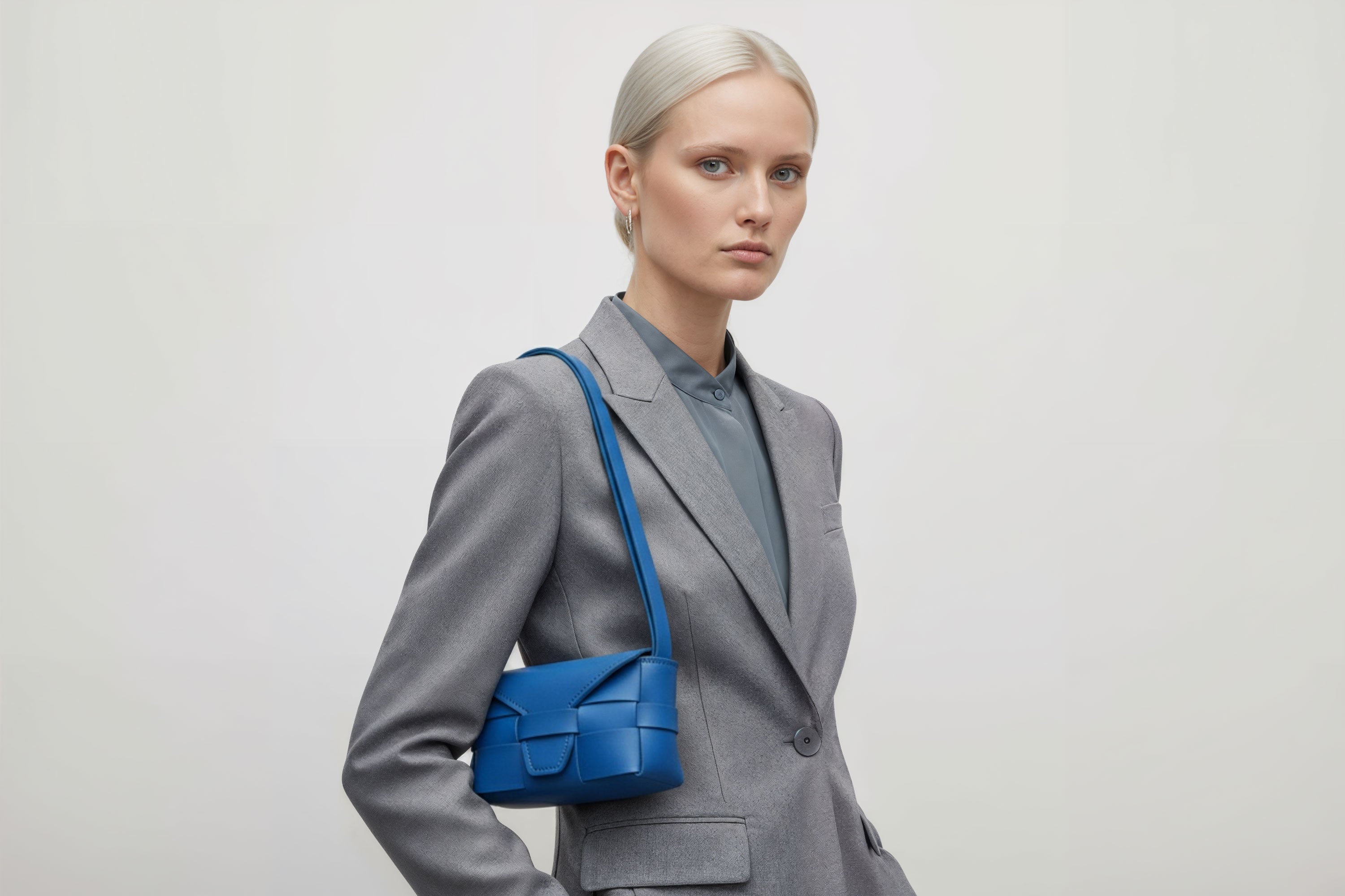 Woman wearing the royal blue small Saka leather bag against a plain background. Minimalist design from Atelier Madre - Manuel Dreesmann in Barcelona