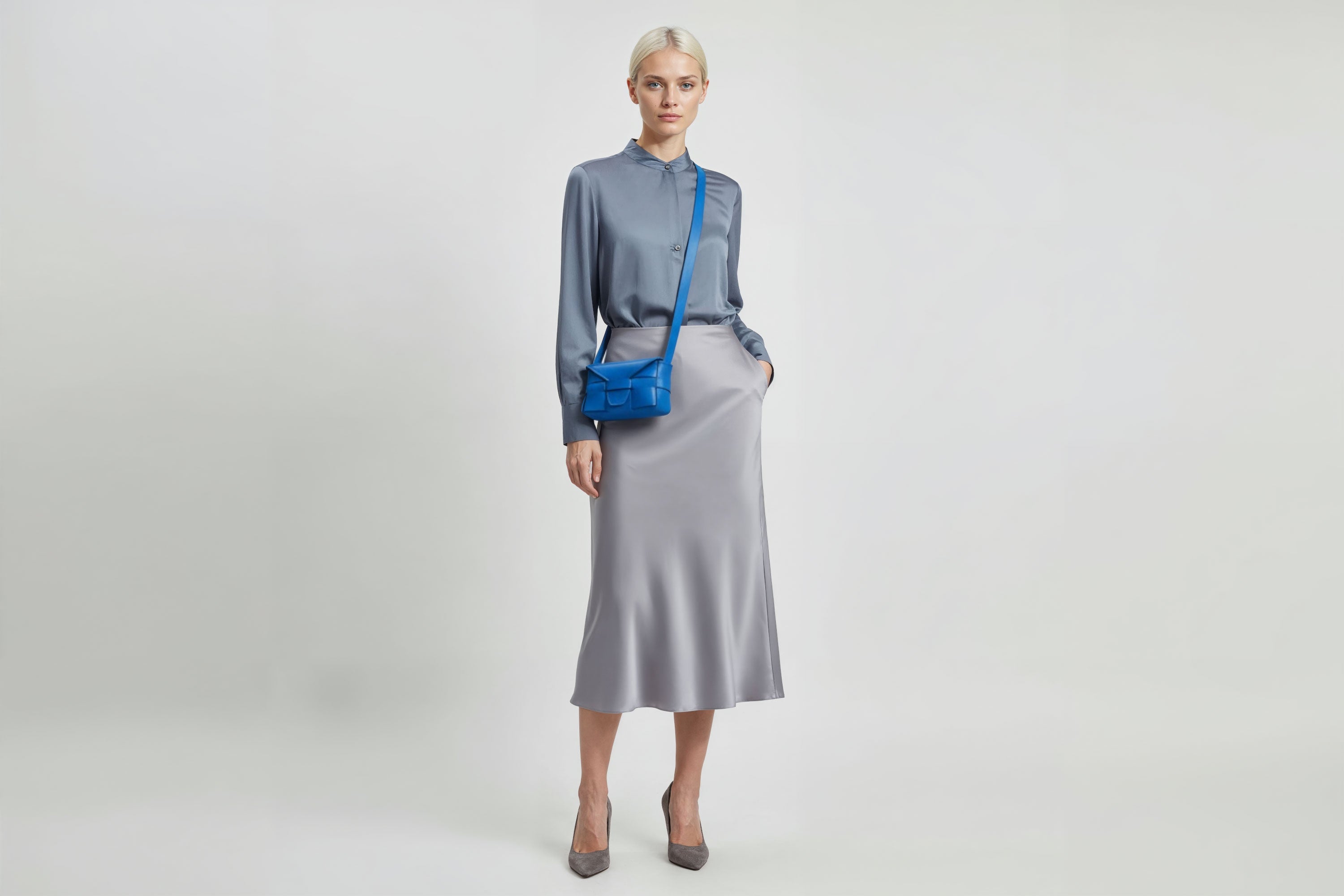 Woman wearing the royal blue small Saka leather bag against a plain background. Minimalist design from Atelier Madre - Manuel Dreesmann in Barcelona
