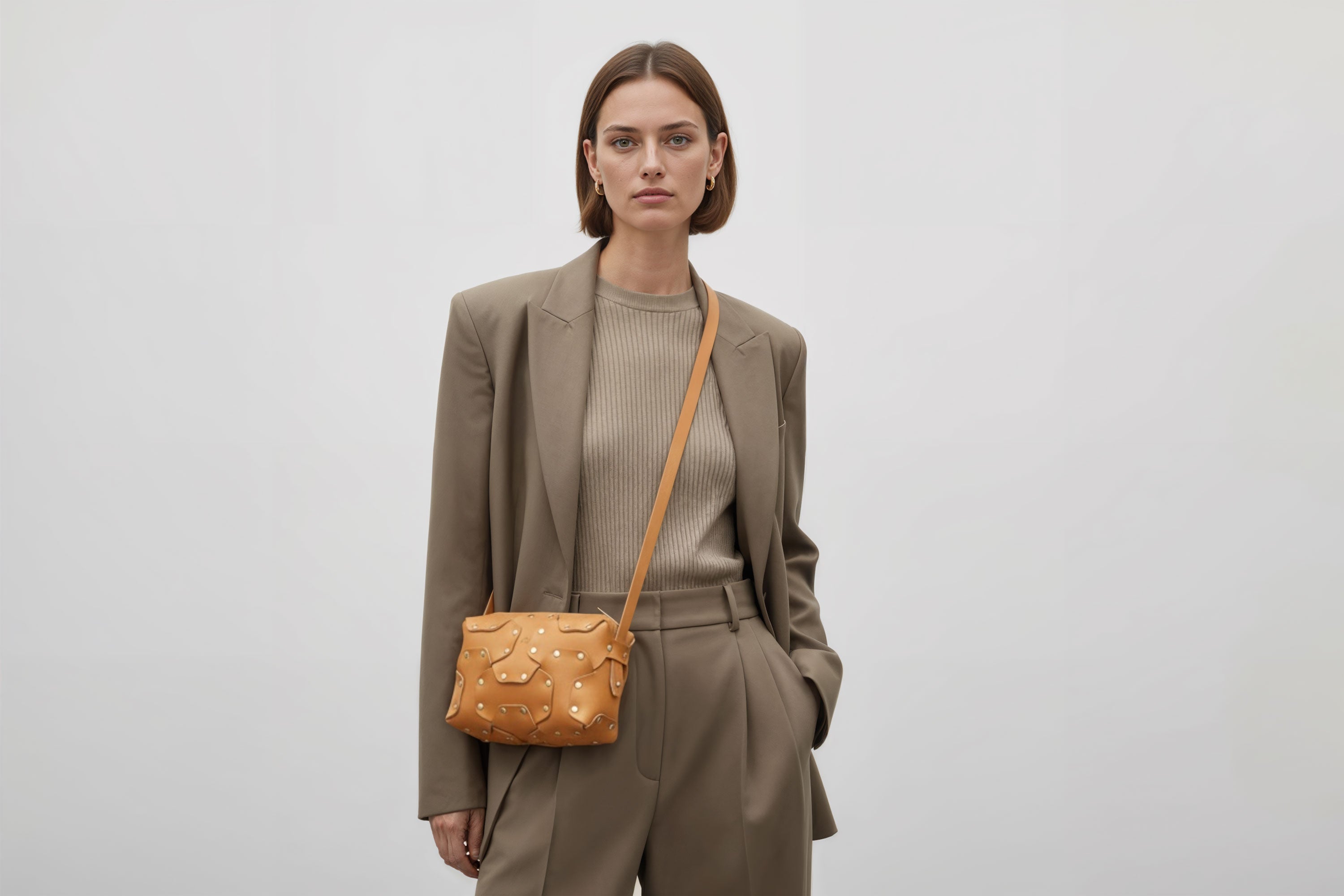 Double Rivet Bag Brown Color On A Woman Model Leather Full Grain Vegetable Tanned Leather Modern Minimalist Design Premium Quality Full Brass Clutch Crossbody Shoulder Bag Atelier Madre Manuel Dreesmann Barcelona Spain