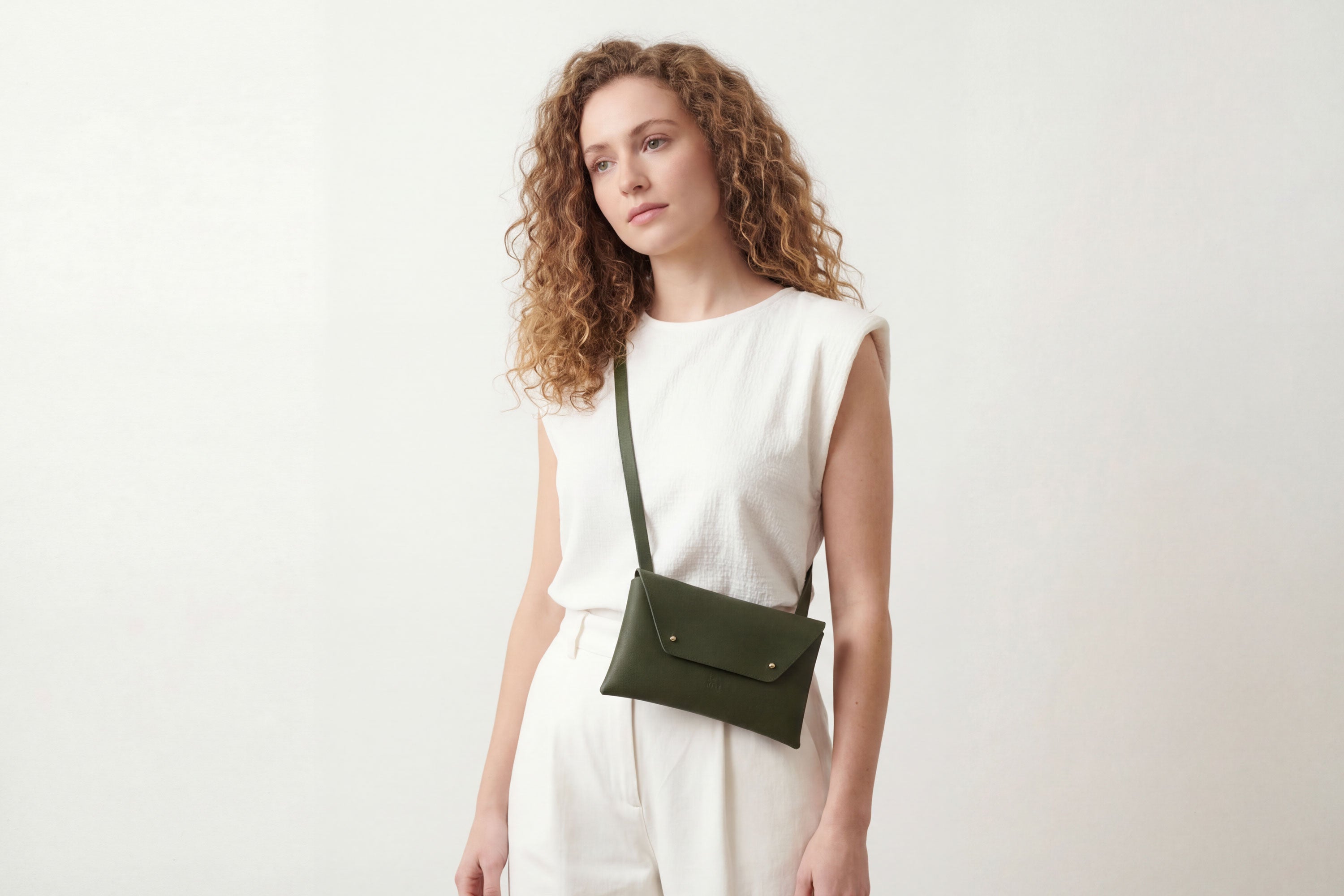 Envelope Bag With a Strap In Olive Green Color On A Woman Model Vegetable Tanned Leather Minimalistic Design Atelier Madre Manuel Dreesmann Barcelona Spain
