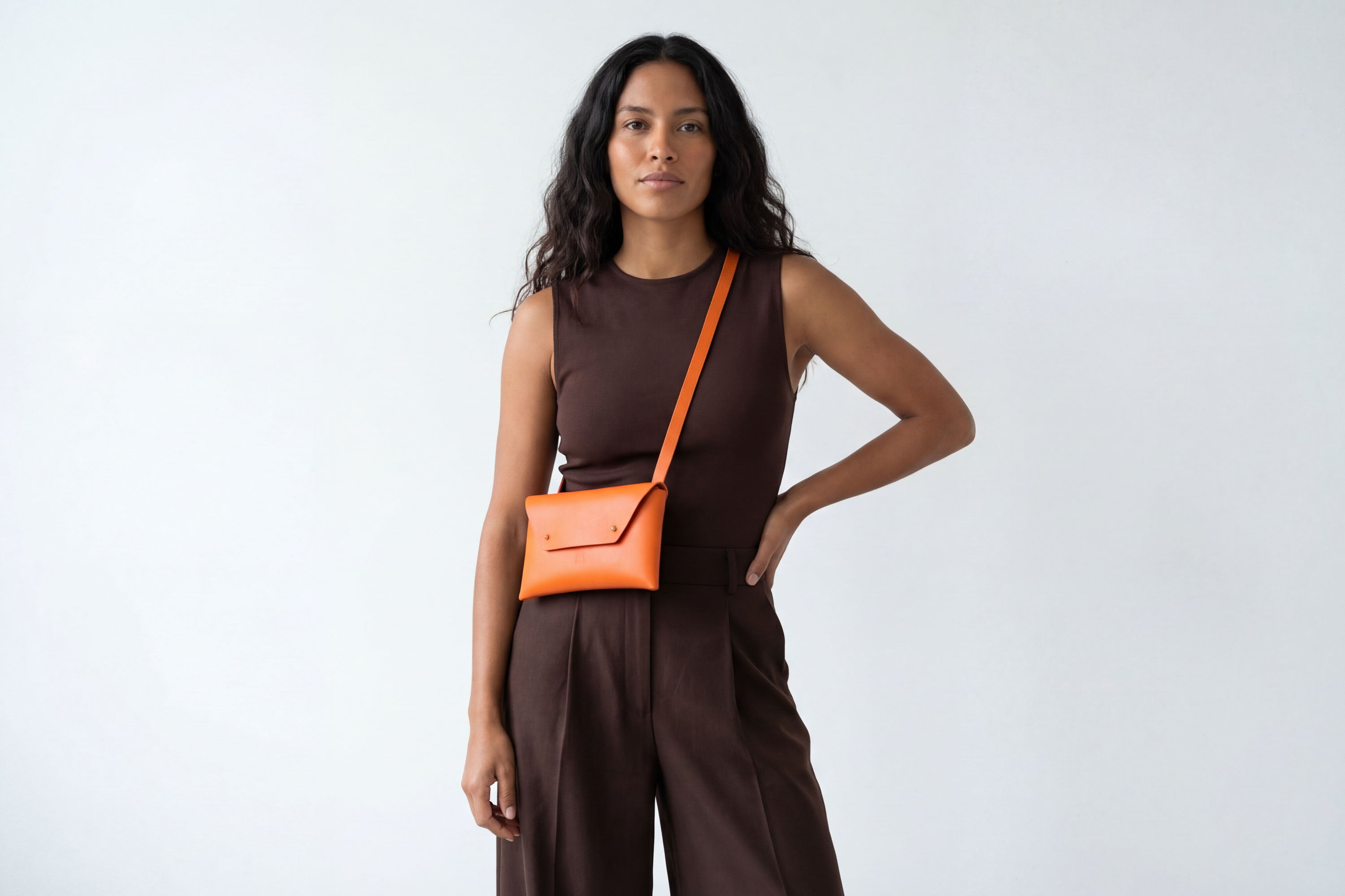 Envelope Bag With a Strap In Orange Color On A Woman Model Vegetable Tanned Leather Minimalistic Design Atelier Madre Manuel Dreesmann Barcelona Spain