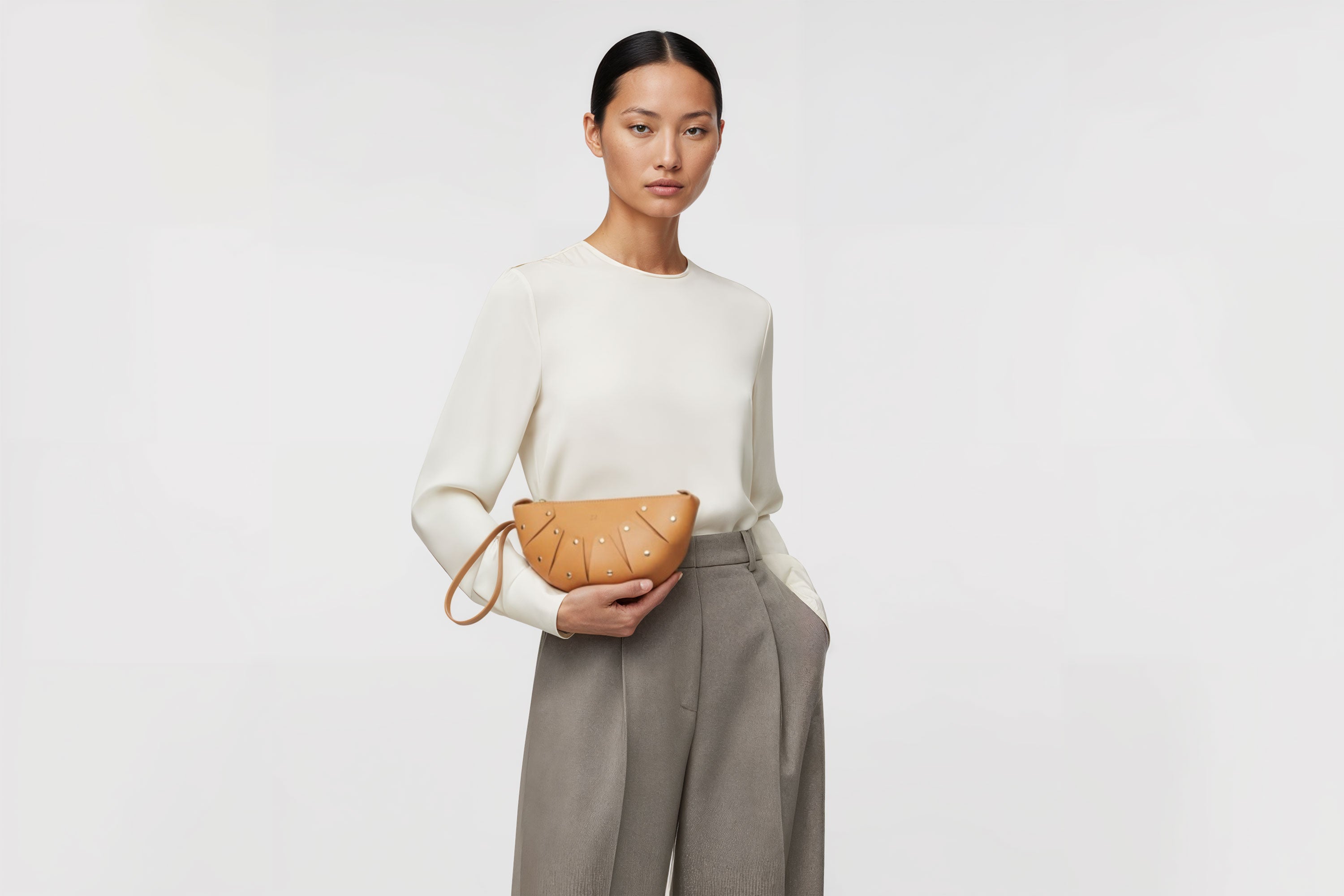 Juno Leather Clutch Bag Brown On A Model Vegetable Tanned Full Grain Spain Brass Rivets Design Minimalist Half Moon Circle Round Zipper Pouch Handbag Clutch Bag Atelier Madre Manuel Dreesmann Barcelona