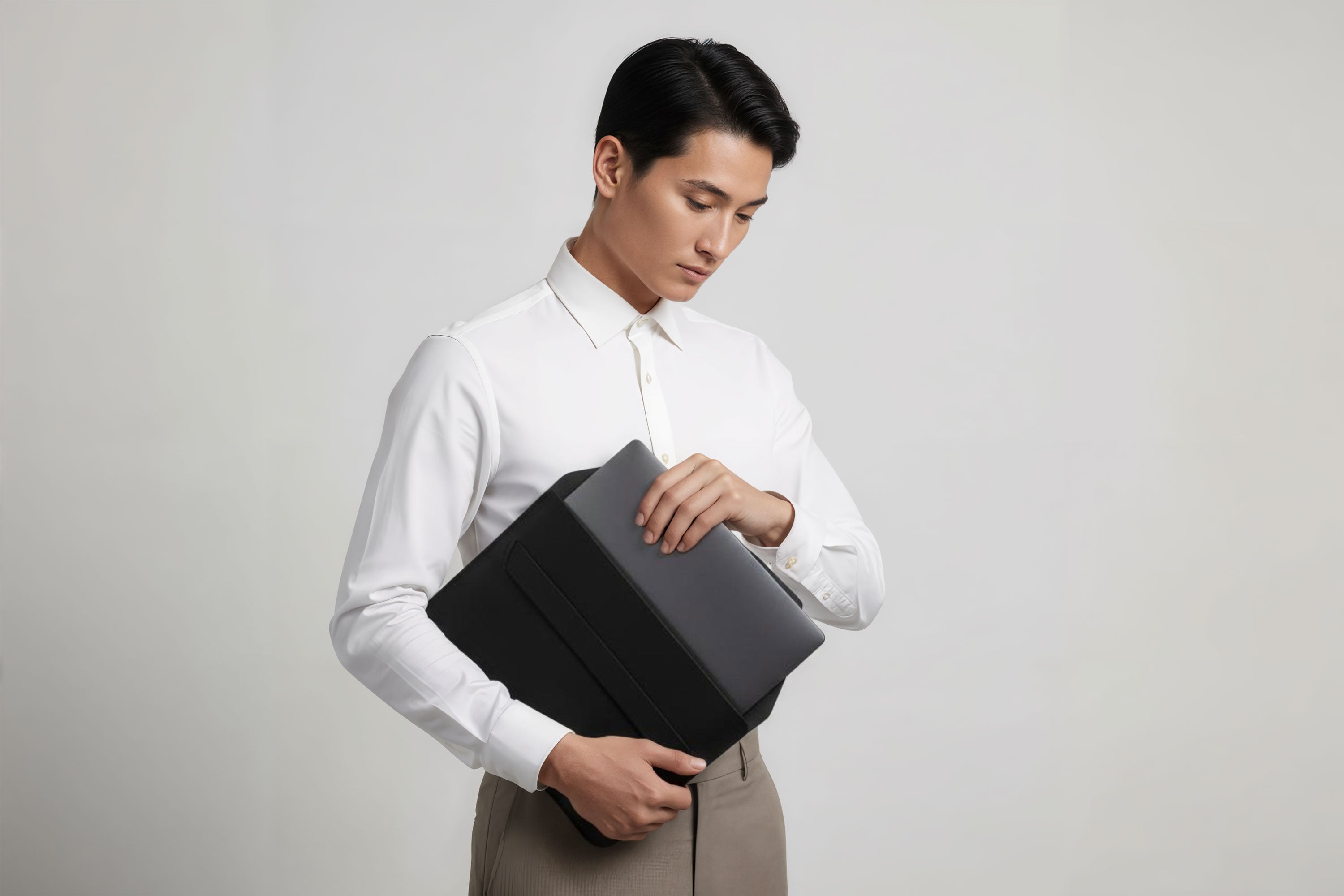 Man holding a leather sleeve for a MacBook in black color in front of bright background minimalistic design atelier Madre Manuel Dreesmann Barcelona Spain