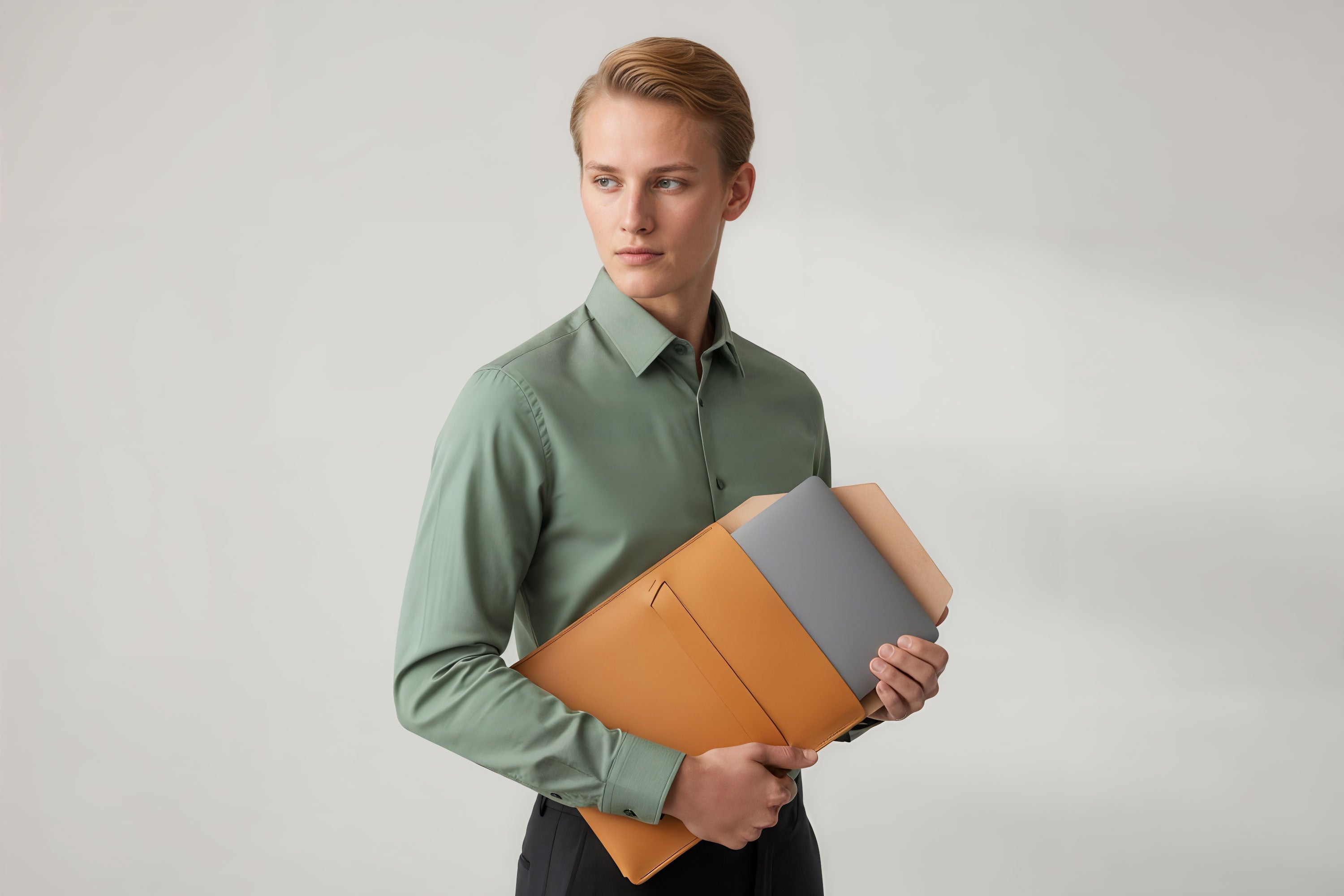 Man holding a leather sleeve for a MacBook in brown color in front of bright background minimalistic design atelier Madre Manuel Dreesmann Barcelona Spain