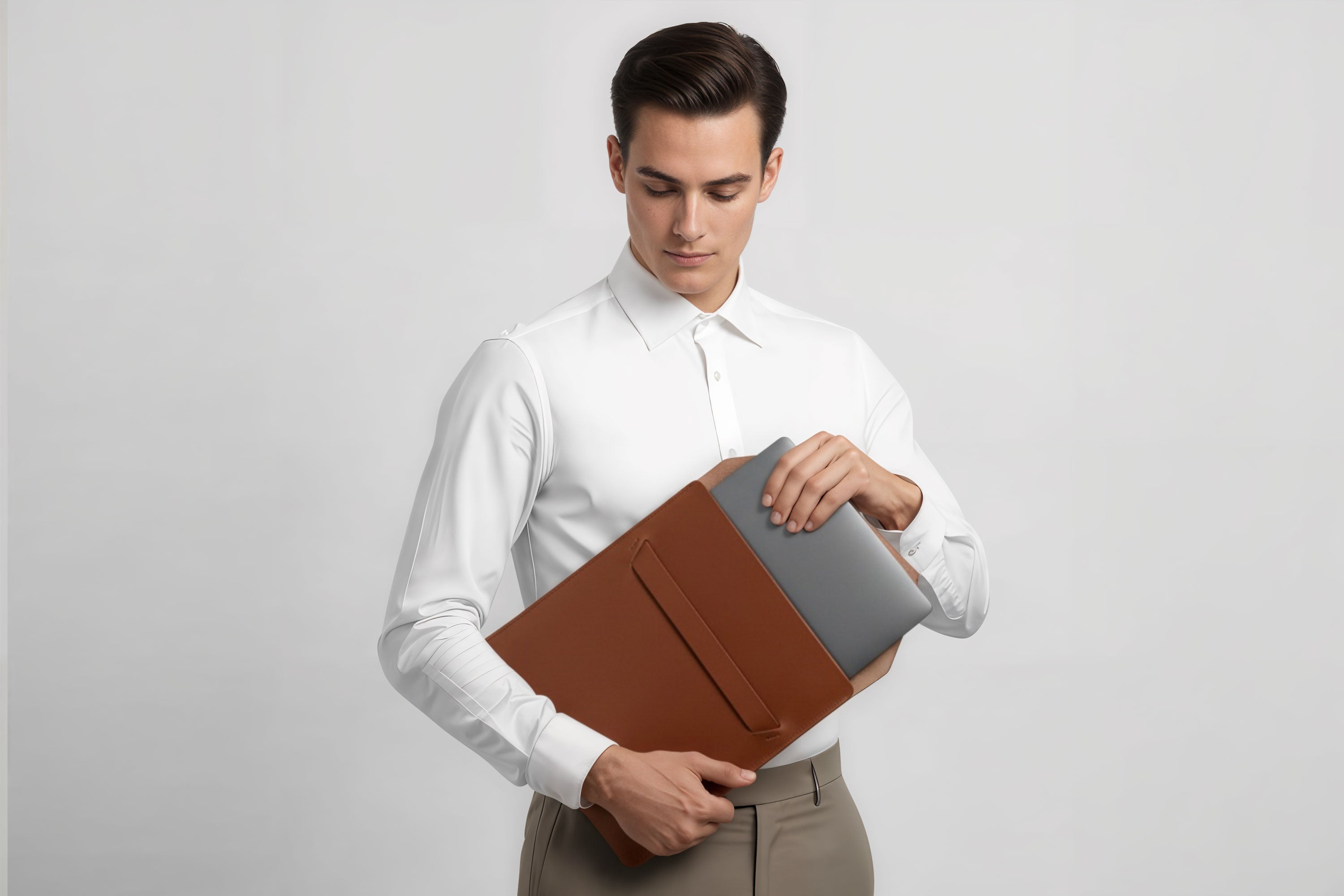 Man holding a leather sleeve for a MacBook in dark brown color in front of bright background minimalistic design atelier Madre Manuel Dreesmann Barcelona Spain