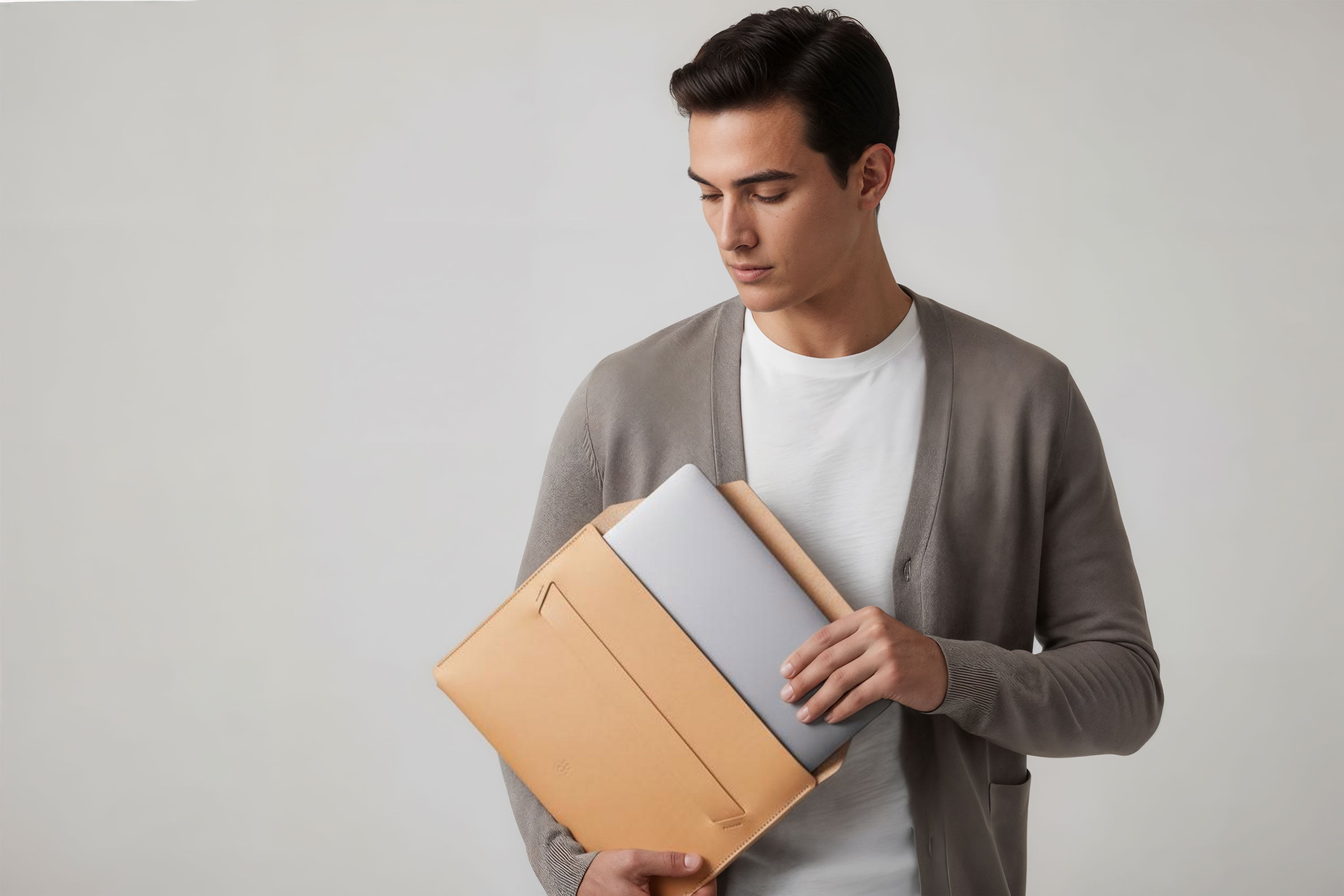 Man holding a leather sleeve for a MacBook in natural color in front of bright background minimalistic design atelier Madre Manuel Dreesmann Barcelona Spain