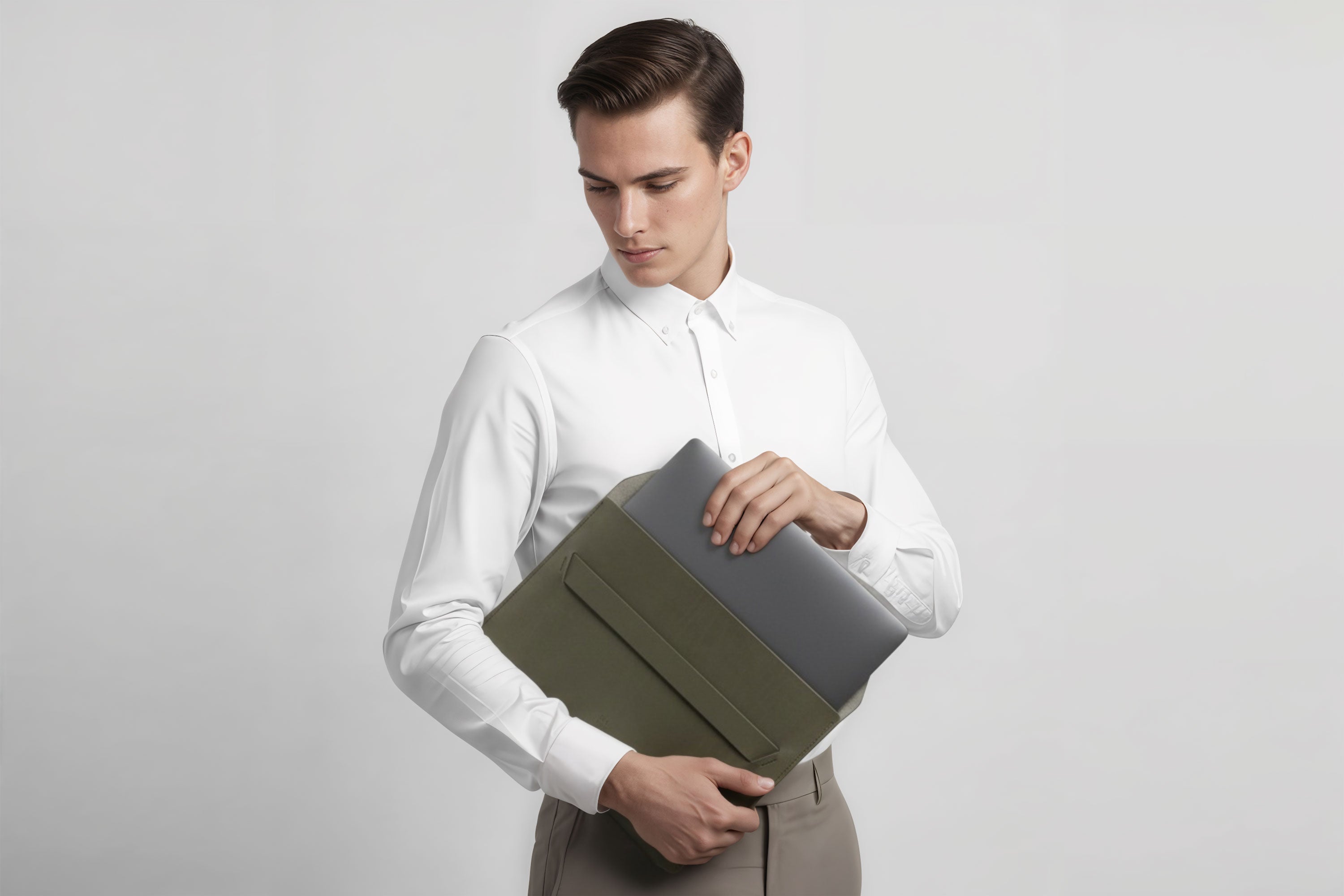 Man holding a leather sleeve for a MacBook in olive green color in front of bright background minimalistic design atelier Madre Manuel Dreesmann Barcelona Spain