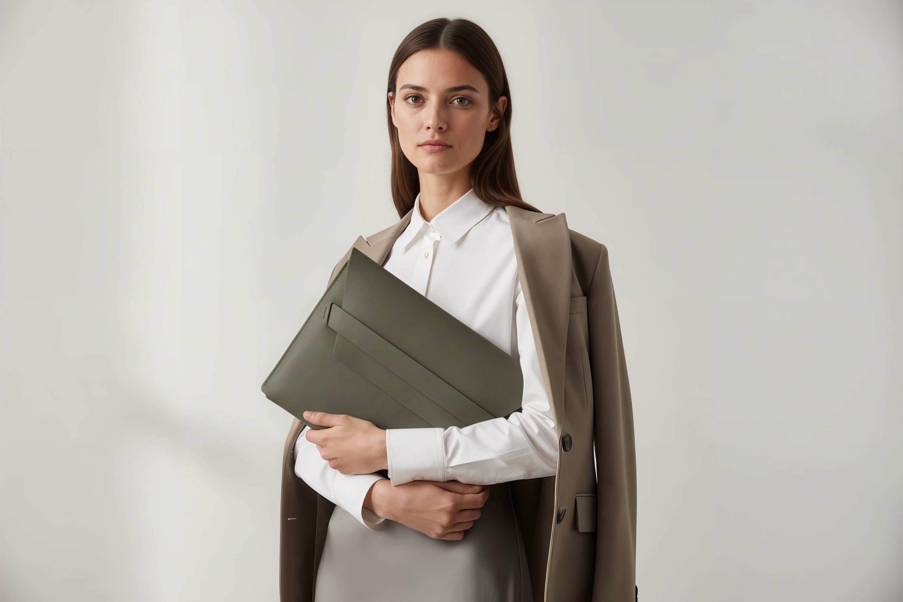 Woman holding a leather sleeve for a MacBook in olive green color in front of bright background minimalistic design atelier Madre Manuel Dreesmann Barcelona Spain
