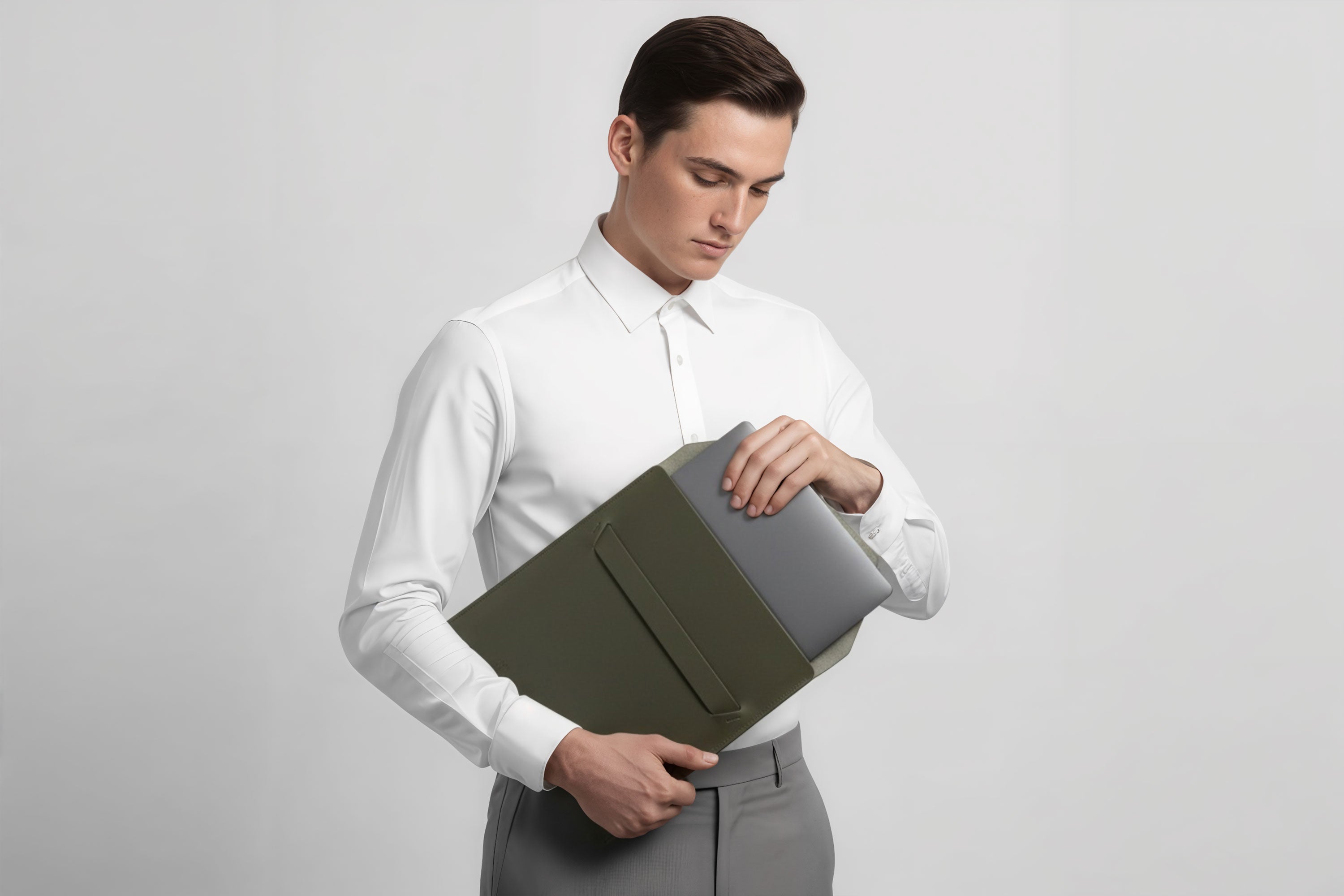 Man holding a leather sleeve for a MacBook in olive green color in front of bright background minimalistic design atelier Madre Manuel Dreesmann Barcelona Spain