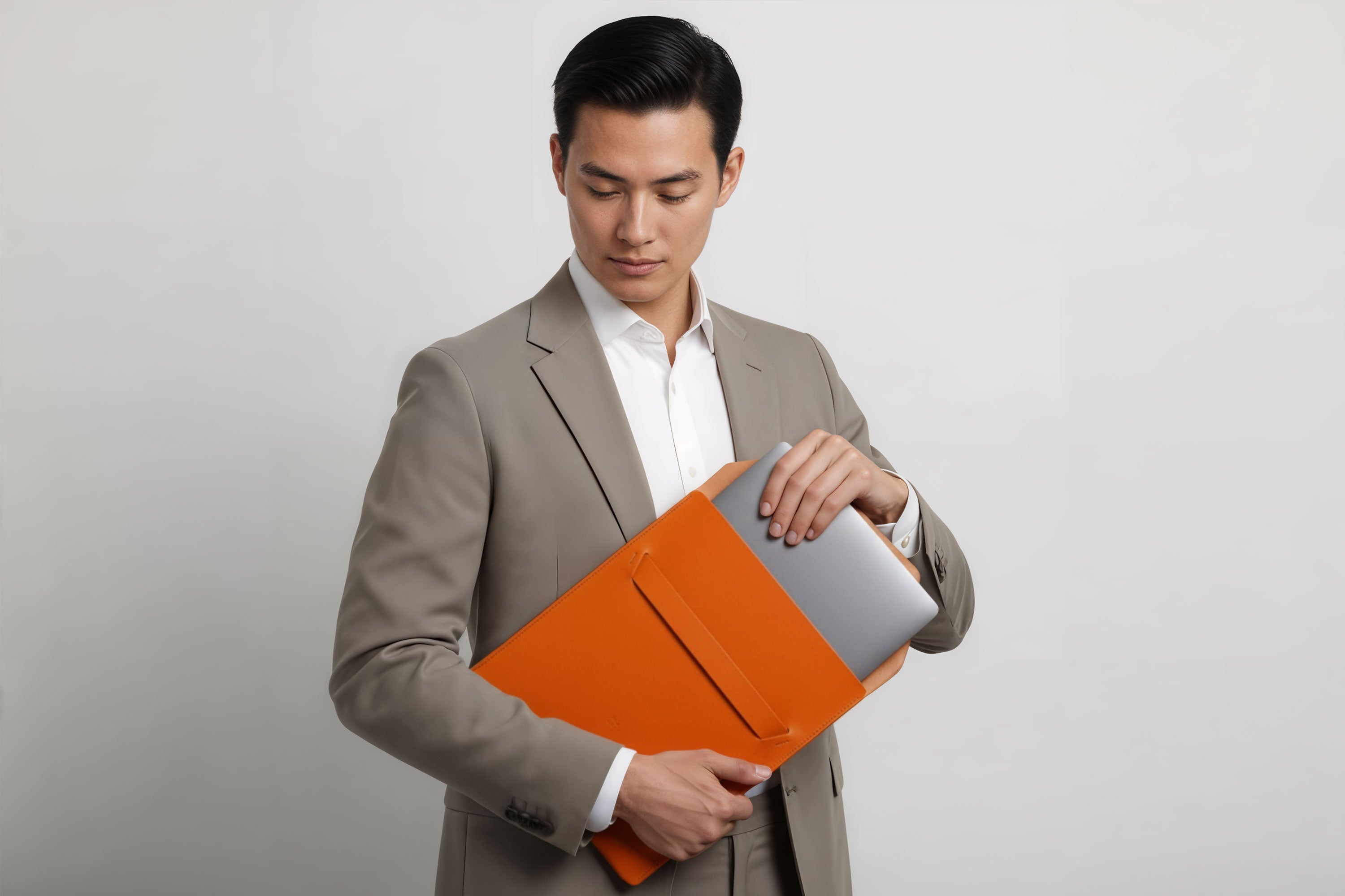 Man holding a leather sleeve for a MacBook in orange color in front of bright background minimalistic design atelier Madre Manuel Dreesmann Barcelona Spain