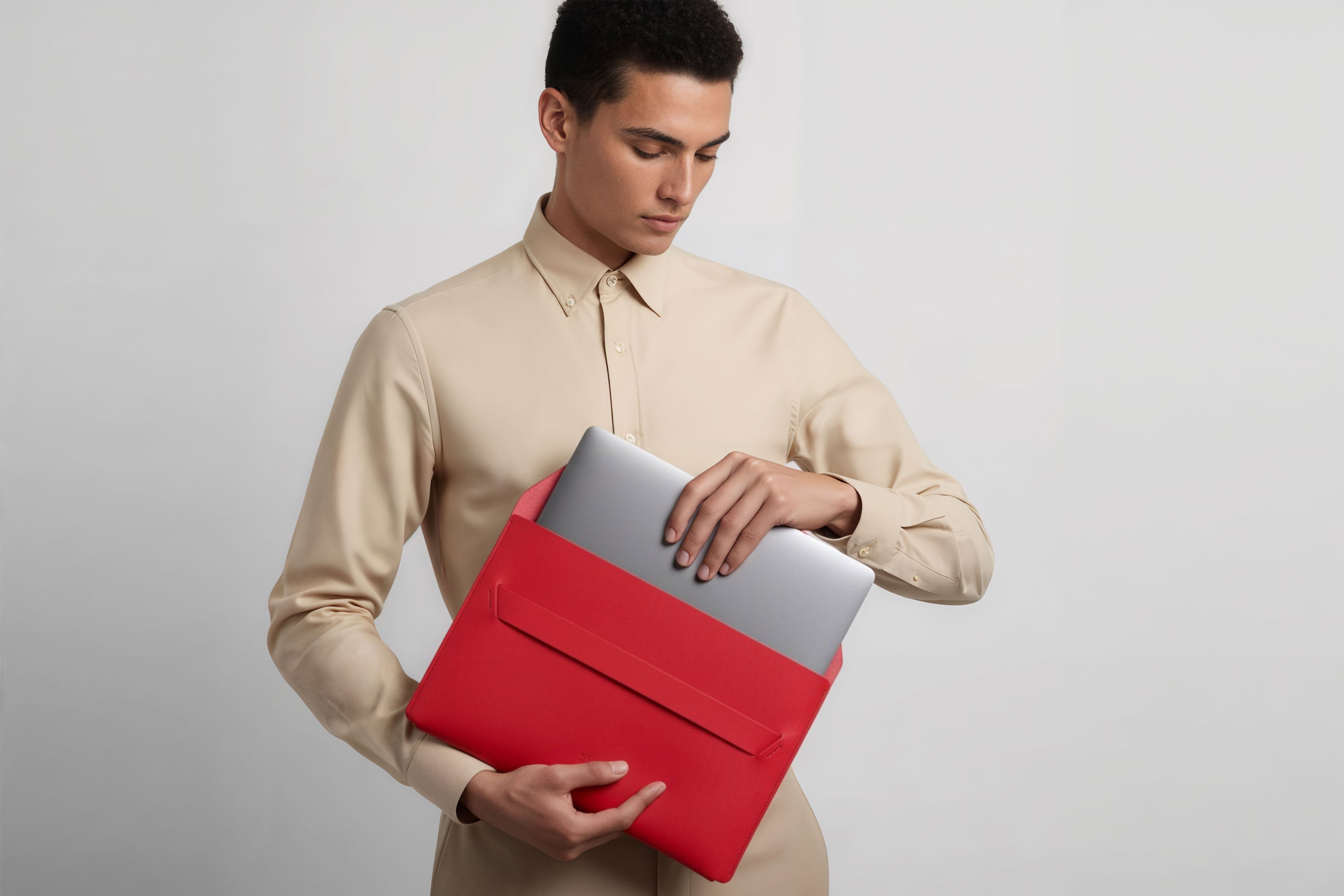 Man holding a leather sleeve for a MacBook in red color in front of bright background minimalistic design atelier Madre Manuel Dreesmann Barcelona Spain