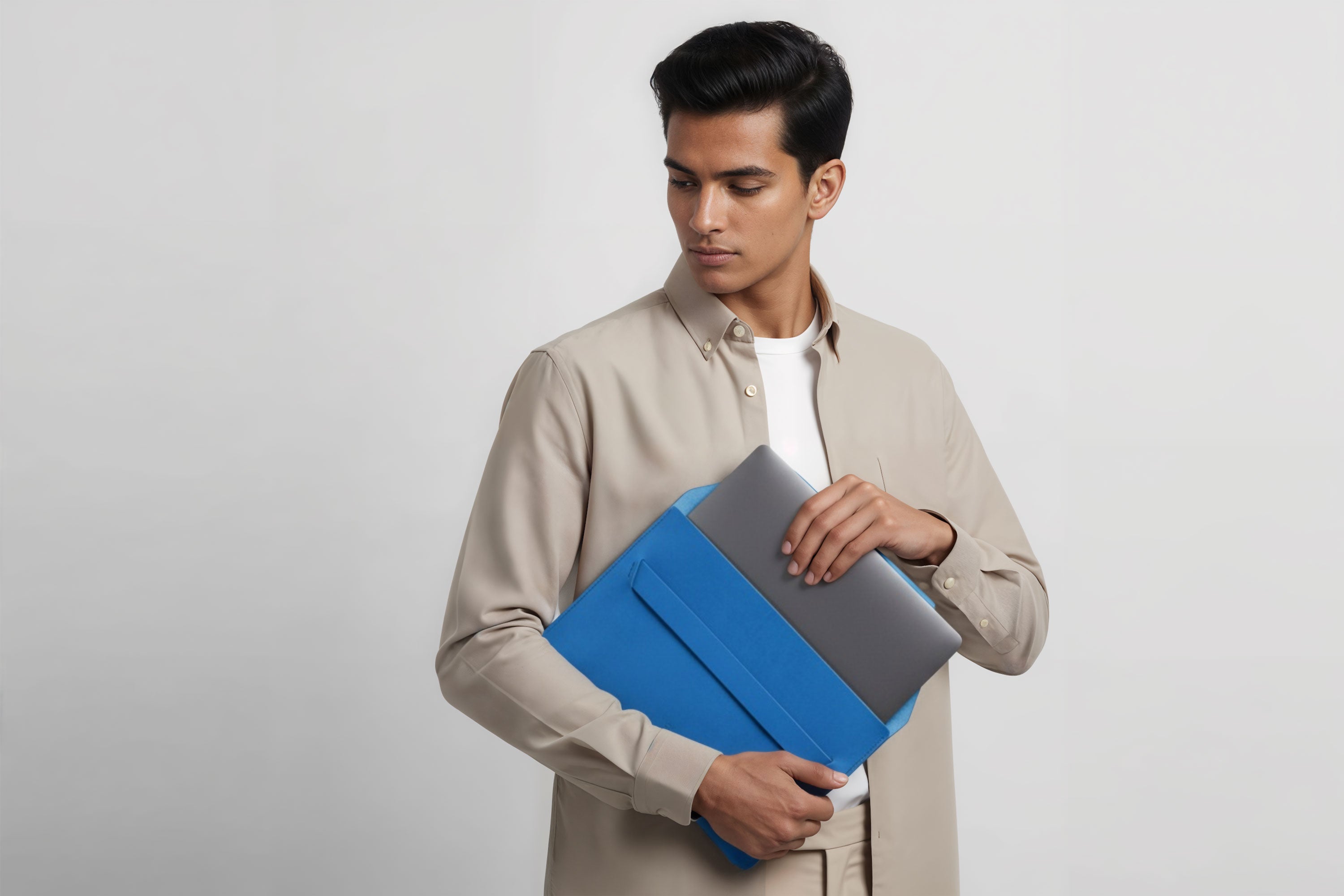 Man holding a leather sleeve for a MacBook in royal blue color in front of bright background minimalistic design atelier Madre Manuel Dreesmann Barcelona Spain