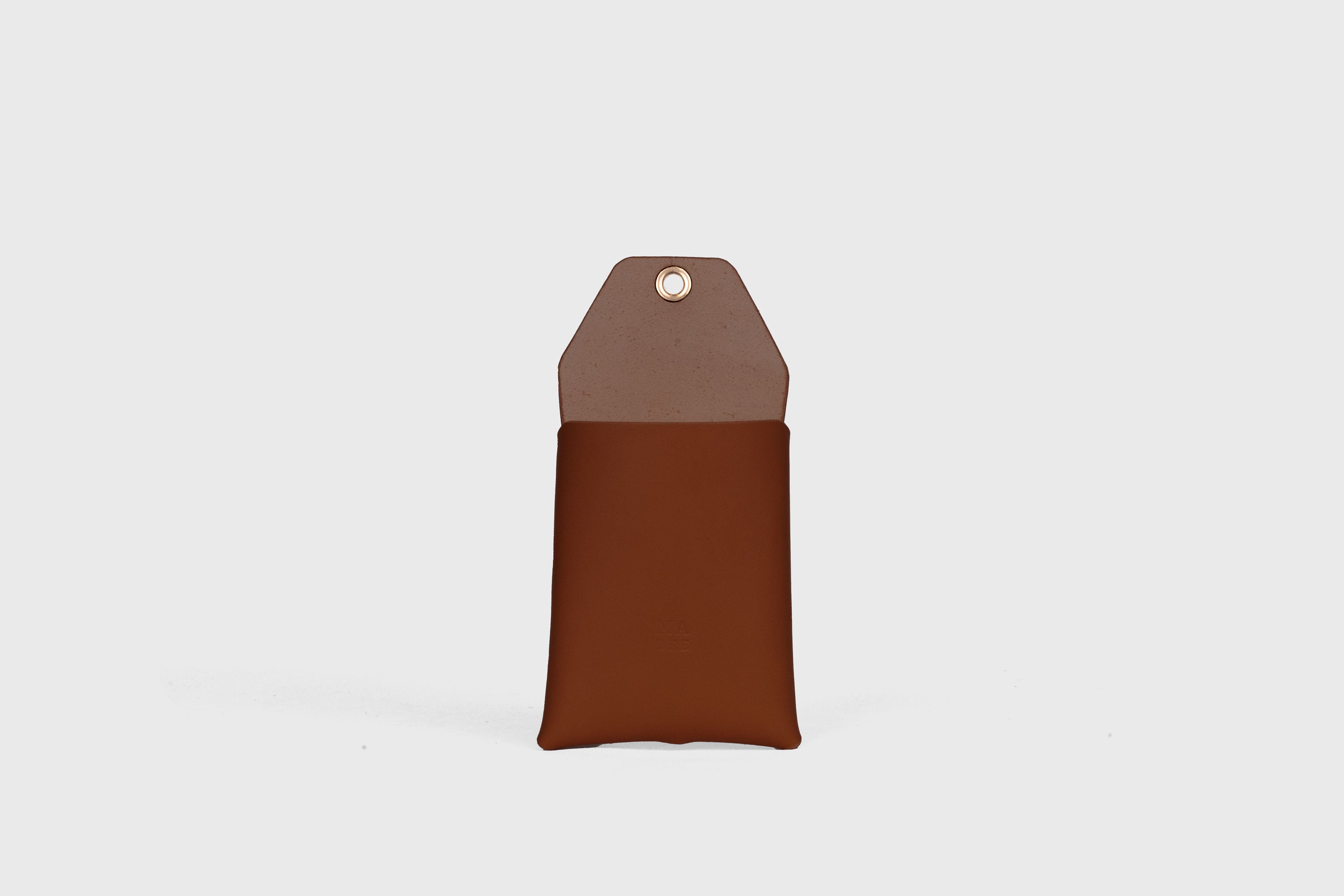 Suporte de parede para telemóvel em castanho escuro em couro curtido vegetal Design minimalista com um ilhó com um orifício para o cabo de carregamento Atelier Madre Manuel Dreesmann Barcelona Espanha