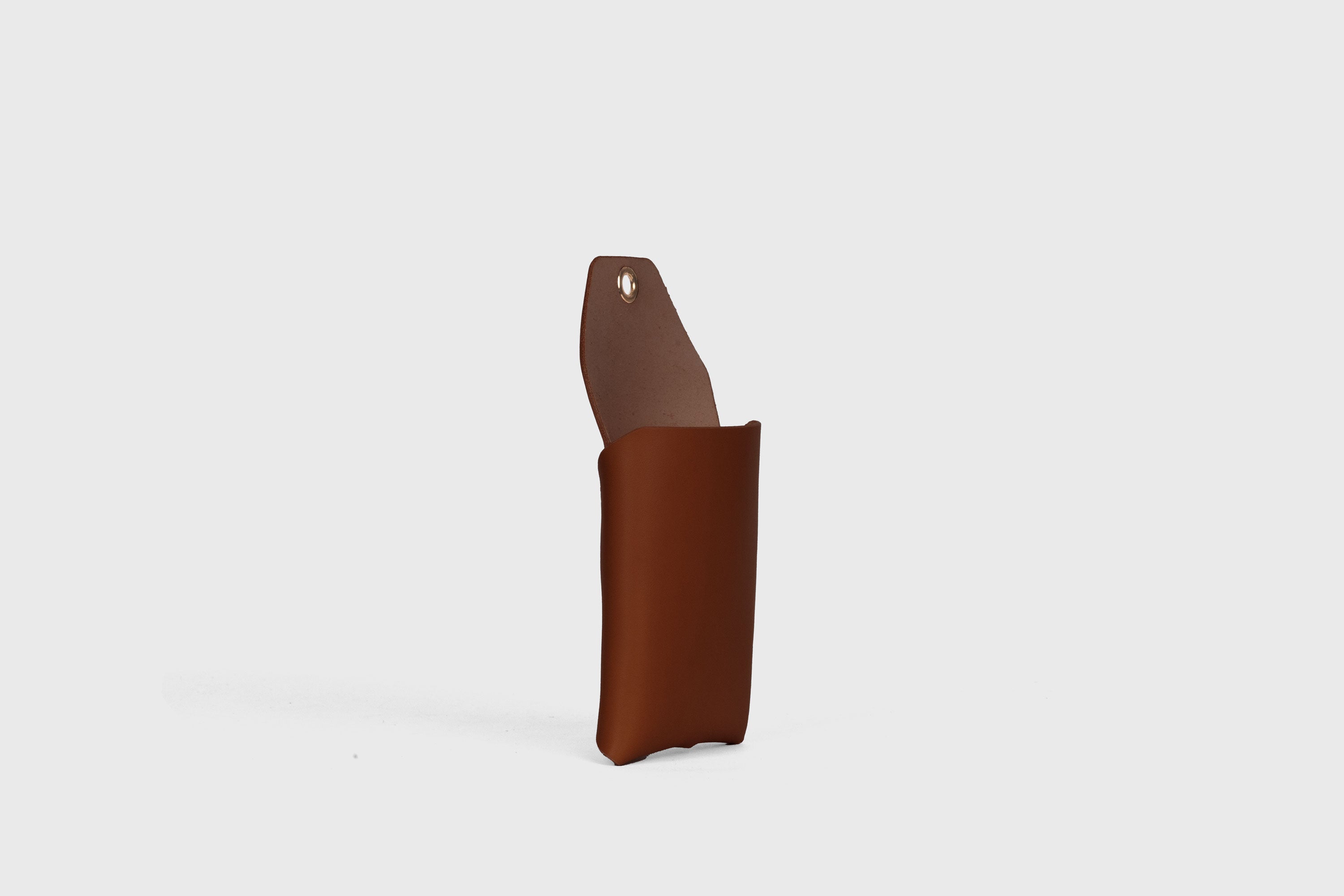 Suporte de parede para telemóvel em castanho escuro em couro curtido vegetal Design minimalista com um ilhó com um orifício para o cabo de carregamento Atelier Madre Manuel Dreesmann Barcelona Espanha