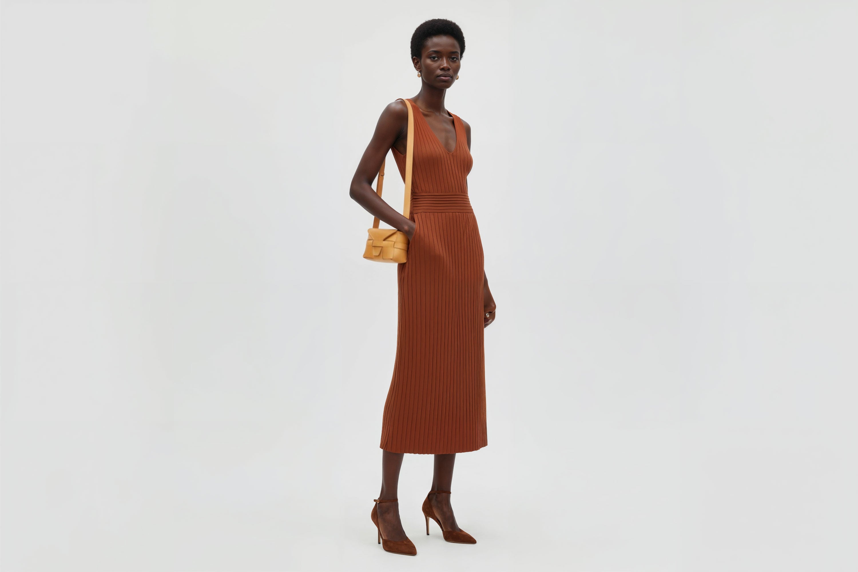 Woman wearing the brown small saka leather bag against a plain background. Minimalist design from Atelier Madre - Manuel Dreesmann in Barcelona