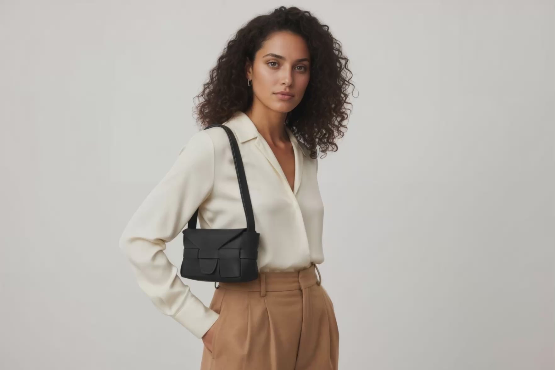 Woman wearing the black small saka leather bag against a plain background. Video Loop Minimalist design from Atelier Madre - Manuel Dreesmann in Barcelona