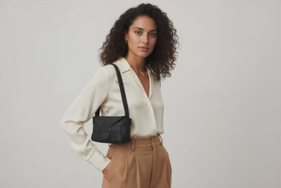 Woman wearing the black small saka leather bag against a plain background. Video Loop Minimalist design from Atelier Madre - Manuel Dreesmann in Barcelona