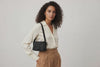 Woman wearing the black small saka leather bag against a plain background. Video Loop Minimalist design from Atelier Madre - Manuel Dreesmann in Barcelona