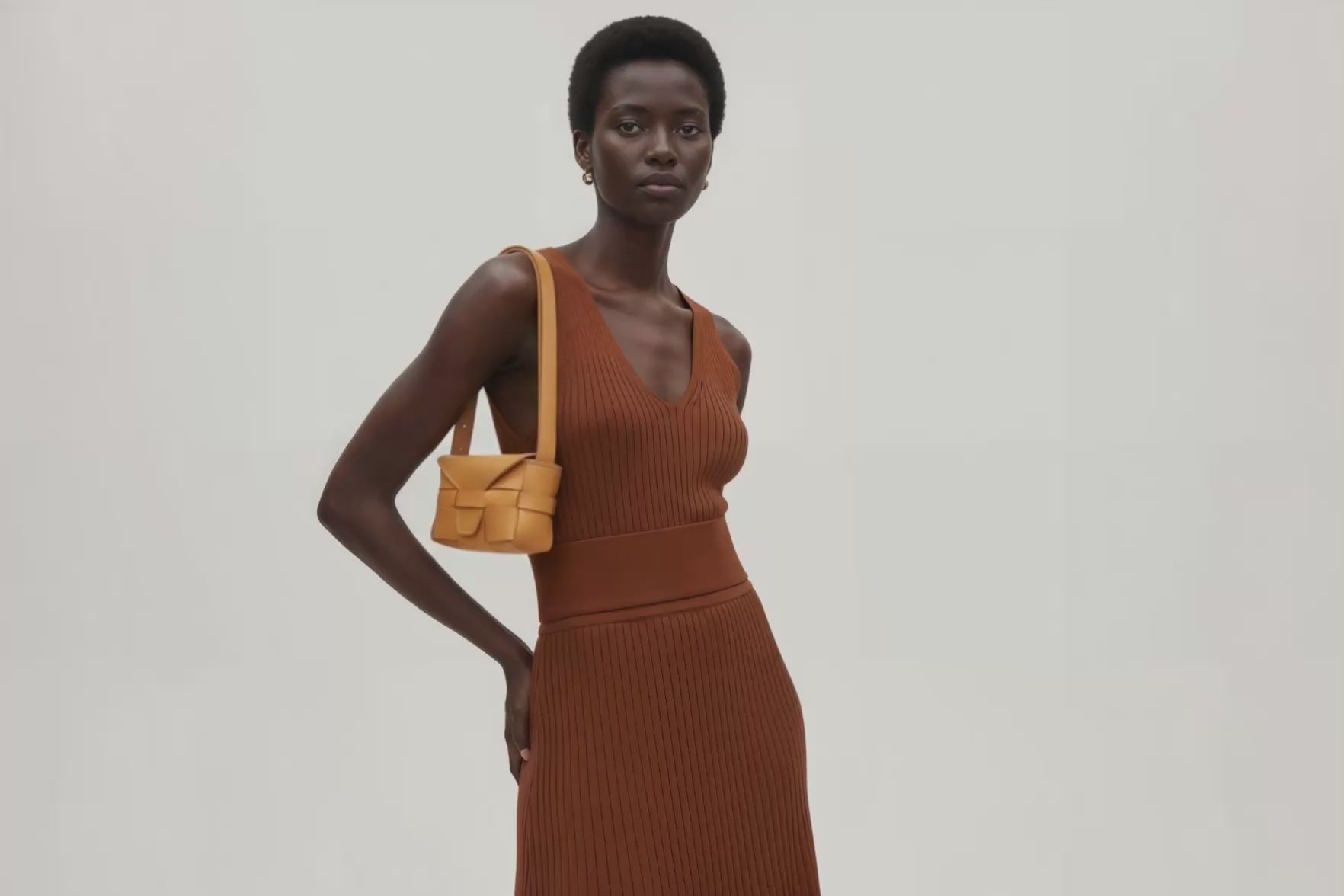 Woman wearing the brown small saka leather bag against a plain background. Video Loop Minimalist design from Atelier Madre - Manuel Dreesmann in Barcelona