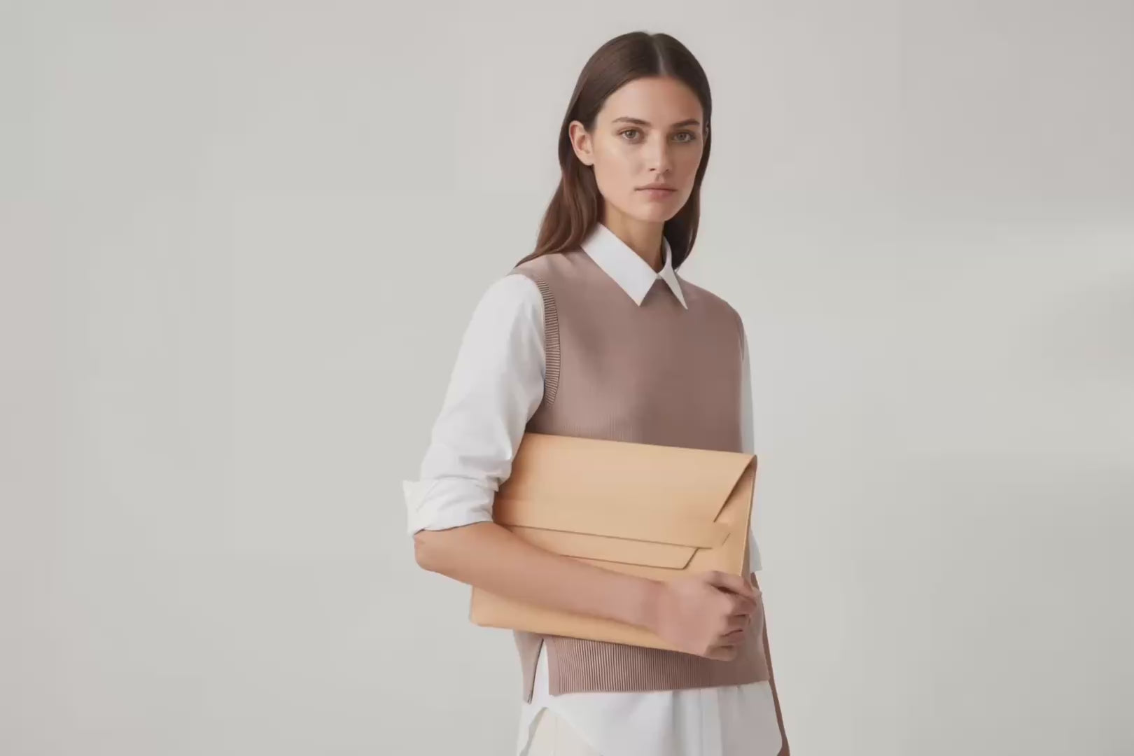 Model is holding a leather sleeve for a MacBook in natural color in front of bright background Video Loop minimalistic design atelier Madre Manuel Dreesmann Barcelona Spain