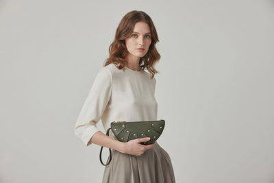 Juno Leather Bag Olive Green Color  On A Model Vegetable Tanned Full Grain Spain Brass Rivets Design Minimalist Half Moon Circle Round Zipper Pouch Handbag Clutch Bag Atelier Madre Manuel Dreesmann Barcelona
