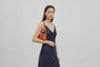Woman wearing the orange small saka leather bag against a plain background. Video Loop Minimalist design from Atelier Madre - Manuel Dreesmann in Barcelona