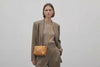 Double Rivet Bag Brown Color On A Woman Model Leather Full Grain Vegetable Tanned Leather Modern Minimalist Design Premium Quality Full Brass Clutch Crossbody Shoulder Bag Atelier Madre Manuel Dreesmann Barcelona Spain