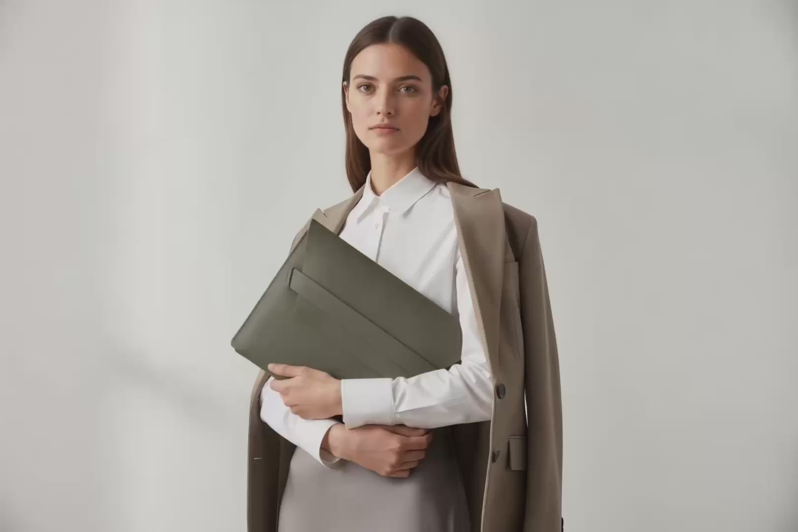 Model is holding a leather sleeve for a MacBook in olive green color in front of bright background Video Loop minimalistic design atelier Madre Manuel Dreesmann Barcelona Spain
