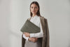 Model is holding a leather sleeve for a MacBook in olive green color in front of bright background Video Loop minimalistic design atelier Madre Manuel Dreesmann Barcelona Spain