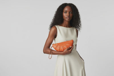 Juno Leather Bag Orange Color On A Model Vegetable Tanned Full Grain Spain Brass Rivets Design Minimalist Half Moon Circle Round Zipper Pouch Handbag Clutch Bag Atelier Madre Manuel Dreesmann Barcelona