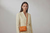 Double Rivet Bag Orange Color On A Woman Model Leather Full Grain Vegetable Tanned Leather Modern Minimalist Design Premium Quality Full Brass Clutch Crossbody Shoulder Bag Atelier Madre Manuel Dreesmann Barcelona Spain