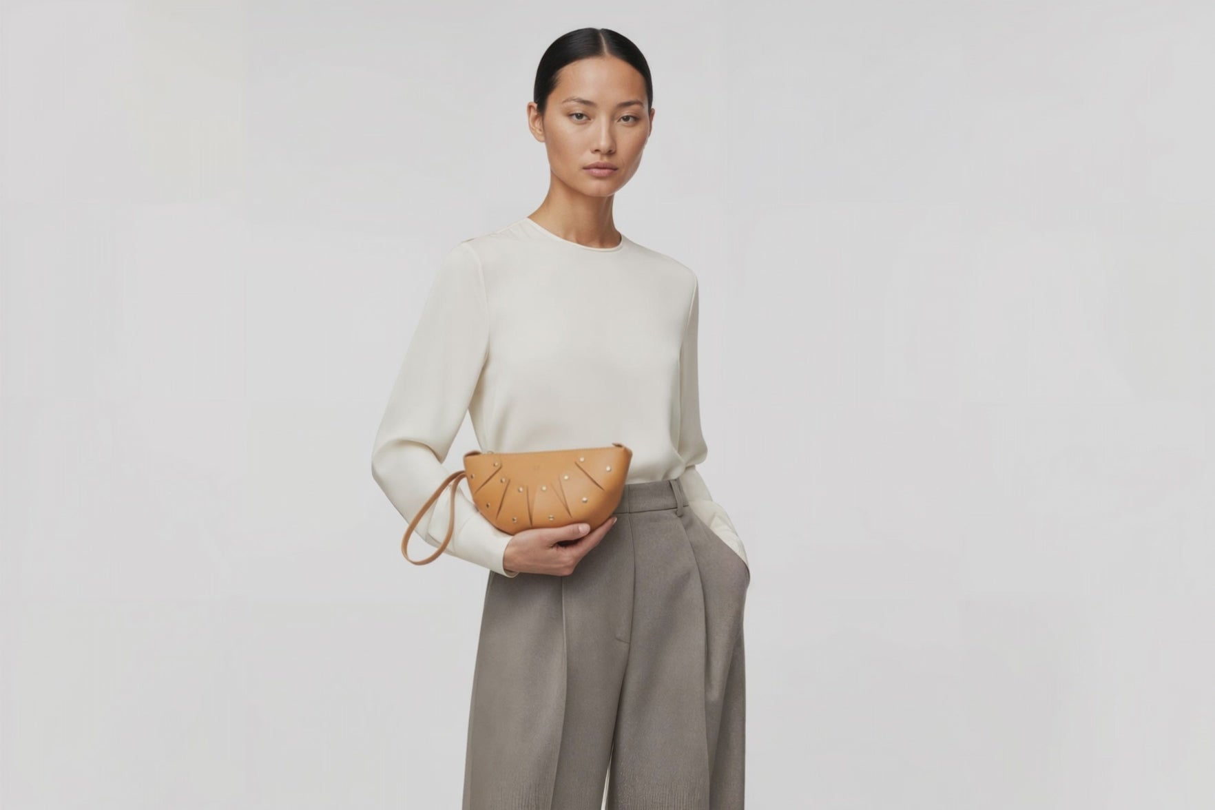 Juno Leather Clutch Bag Brown On A Model Vegetable Tanned Full Grain Spain Brass Rivets Design Minimalist Half Moon Circle Round Zipper Pouch Handbag Clutch Bag Atelier Madre Manuel Dreesmann Barcelona