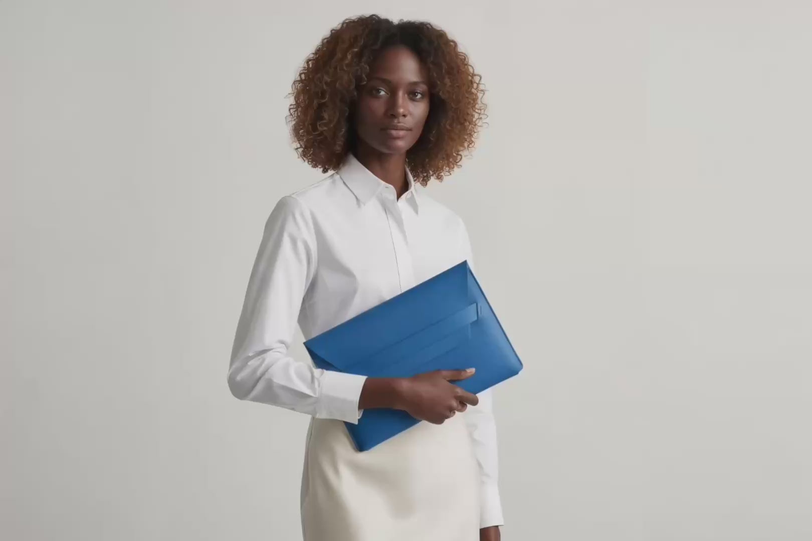 Model is holding a leather sleeve for a MacBook in royal blue color in front of bright background Video Loop minimalistic design atelier Madre Manuel Dreesmann Barcelona Spain