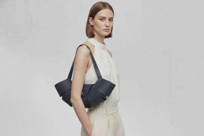Croissant Bag Marine Blue Color Leather Magnetic Closure On A Woman Model Full Grain Vegetable Tanned Leather High Quality Modern Minimalistic Organic Design Full Brass Rivets Atelier Madre Manuel Dreesmann Barcelona Spain