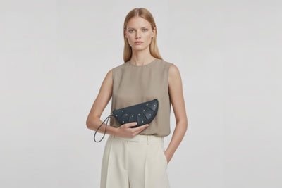 Juno Leather Bag Marine Blue Color On A Model Vegetable Tanned Full Grain Spain Brass Rivets Design Minimalist Half Moon Circle Round Zipper Pouch Handbag Clutch Bag Atelier Madre Manuel Dreesmann Barcelona