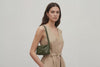 Woman wearing the olive green small saka leather bag against a plain background. Video Loop Minimalist design from Atelier Madre - Manuel Dreesmann in Barcelona