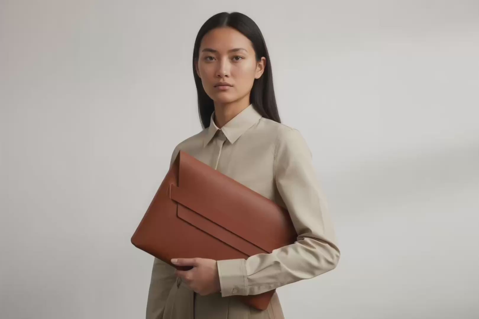 Model is holding a leather sleeve for a MacBook in dark brown color in front of bright background Video Loop minimalistic design atelier Madre Manuel Dreesmann Barcelona Spain