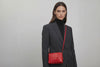 Double Rivet Bag Red Color On A Woman Model Leather Full Grain Vegetable Tanned Leather Modern Minimalist Design Premium Quality Full Brass Clutch Crossbody Shoulder Bag Atelier Madre Manuel Dreesmann Barcelona Spain