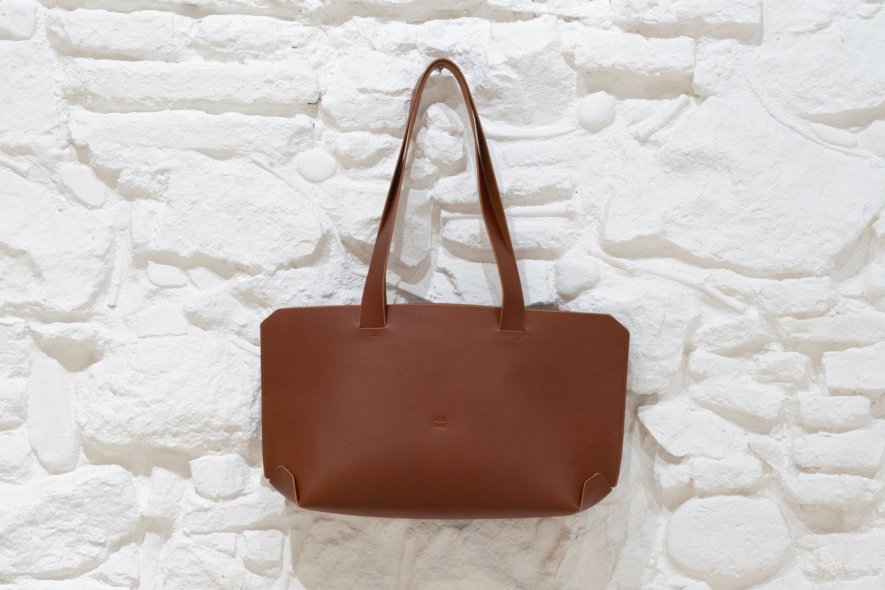 Tote Bag Dark Brown Vegetable Tanned Leather Hanging on Wall White Bricks Premium Quality German Design By Manuel Dreesmann Atelier Madre Barcelona Spain